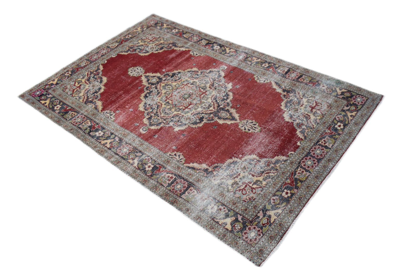 A vintage Persian Kerman rug featuring a central medallion and intricate floral patterns in red.