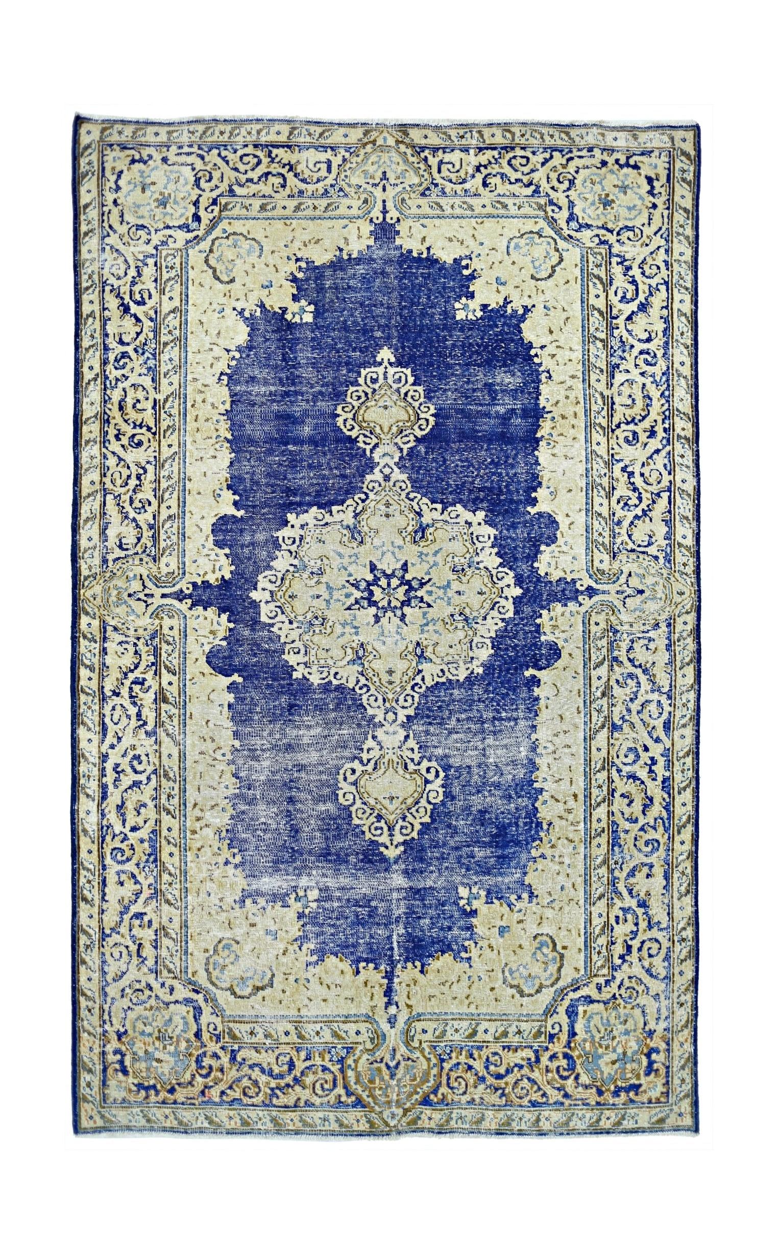 A vintage Persian Kerman rug featuring a central medallion and floral motifs in blue and cream.