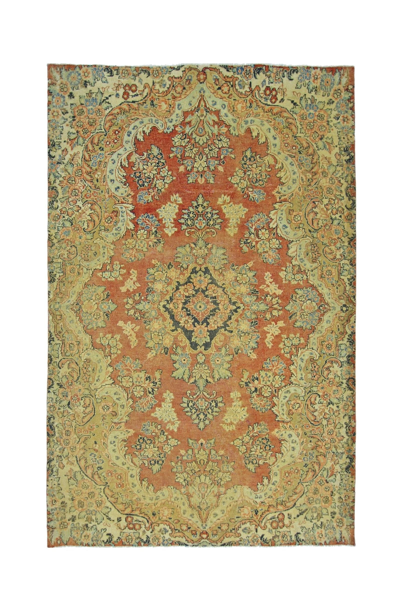 A vintage Persian Kerman rug featuring a central medallion and intricate floral patterns in red.