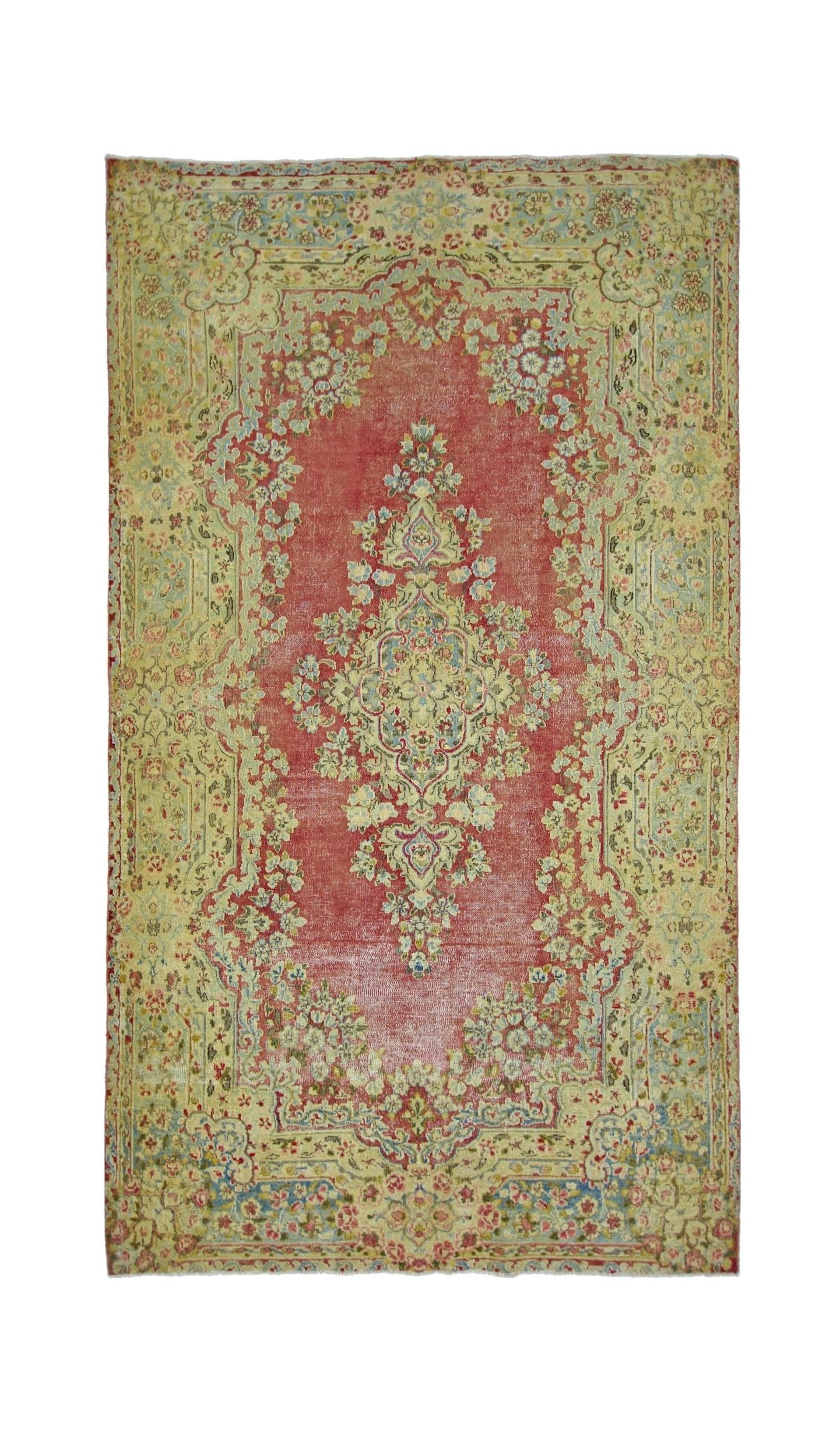 A vintage Persian Kerman rug featuring a central floral medallion on a red field with ornate borders.