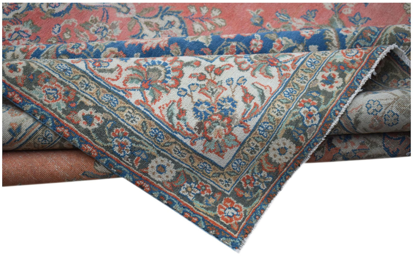 A vintage Persian Kerman rug featuring a floral pattern in shades of red, blue, and cream.