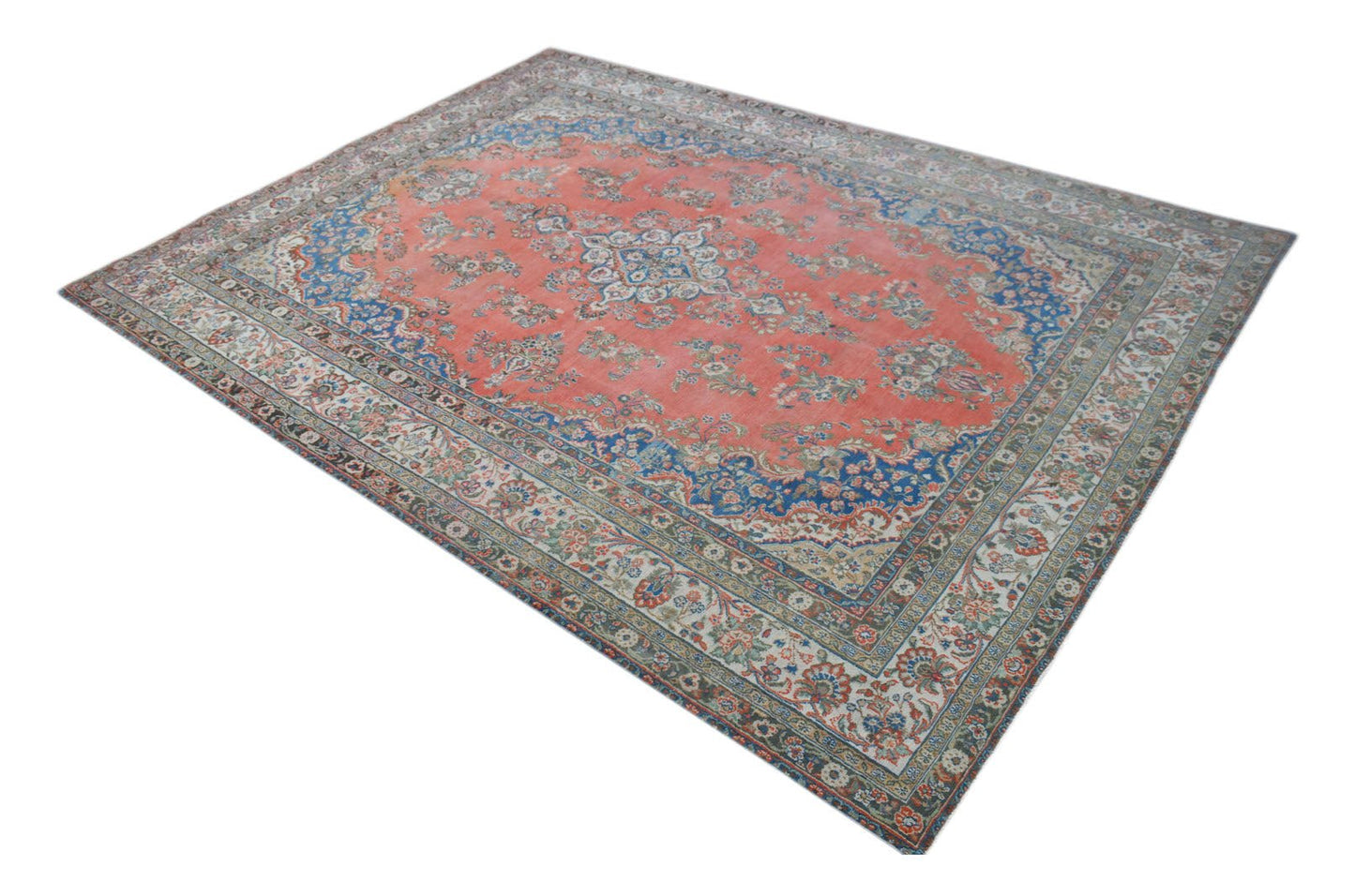 A vintage Persian Kerman rug featuring a central medallion and intricate floral patterns in red.