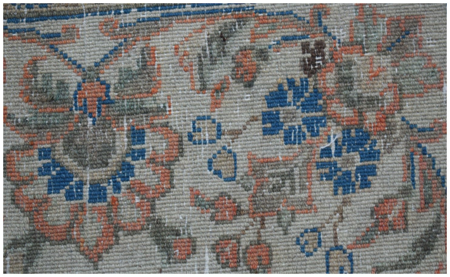 A close-up of a vintage Persian Kerman rug featuring intricate floral patterns in blue and orange.