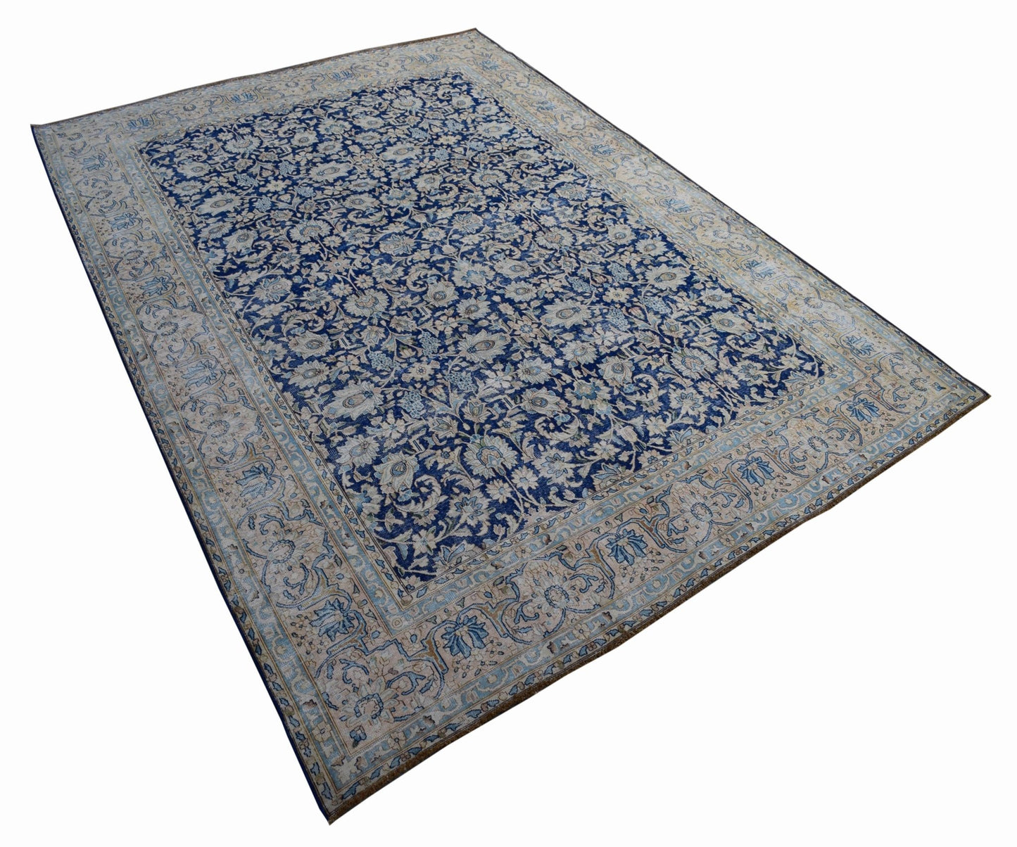 A vintage Persian Kerman rug featuring an intricate floral pattern in blue and cream tones.
