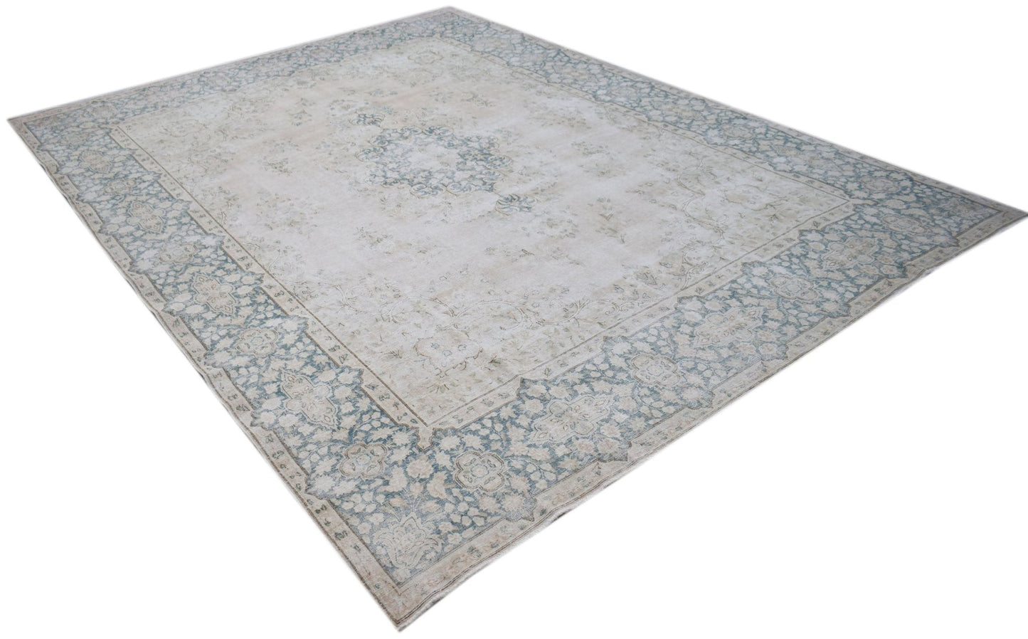 A vintage Persian Kerman rug featuring a central medallion and intricate floral border in soft tones.