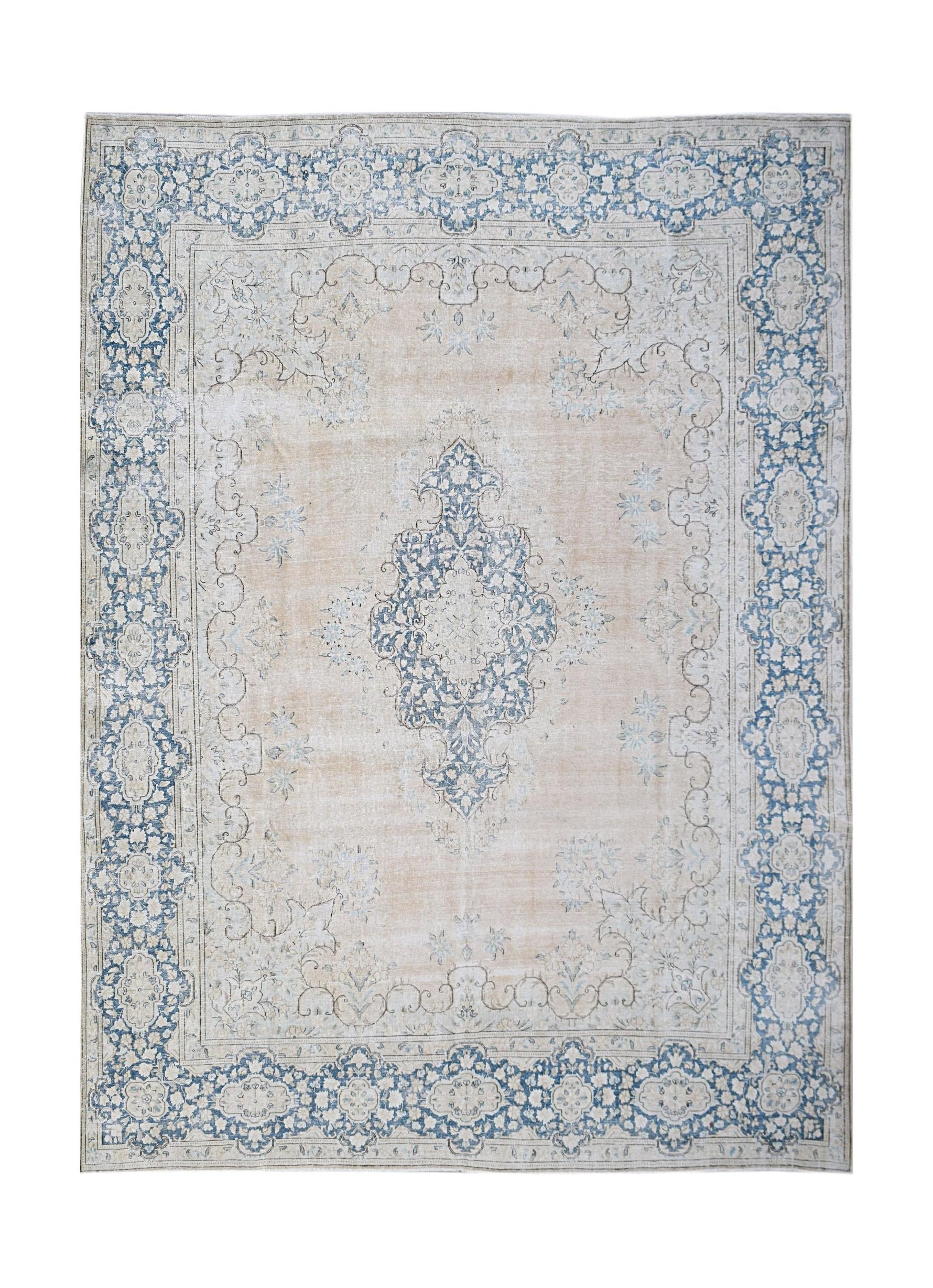 A vintage Persian Kerman rug featuring a central blue medallion on a soft beige floral field.