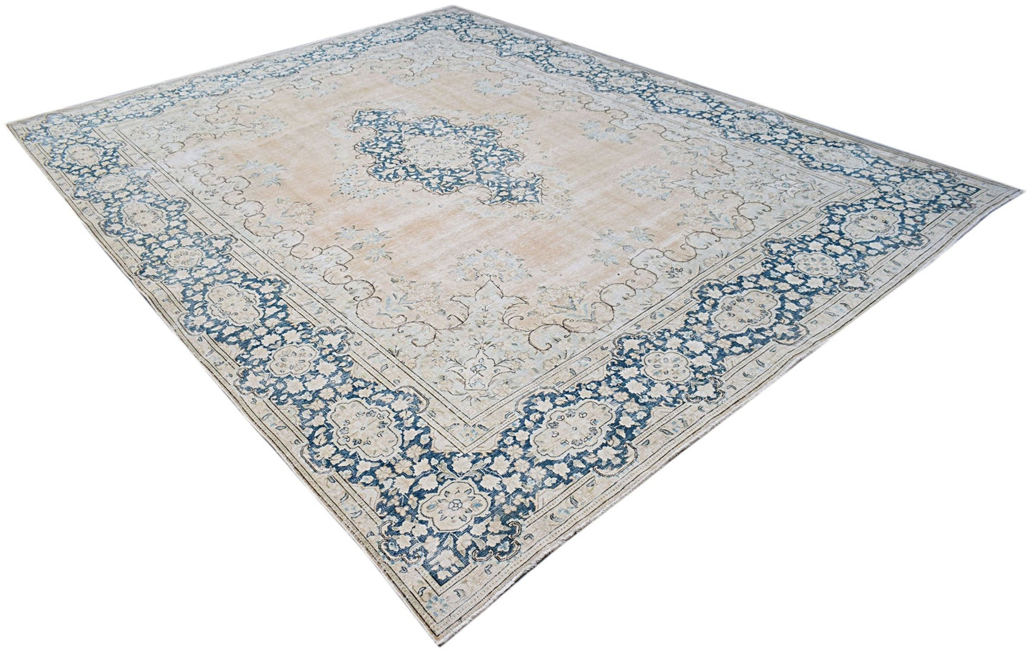A vintage Persian Kerman rug featuring a central medallion and floral motifs in blue and beige.
