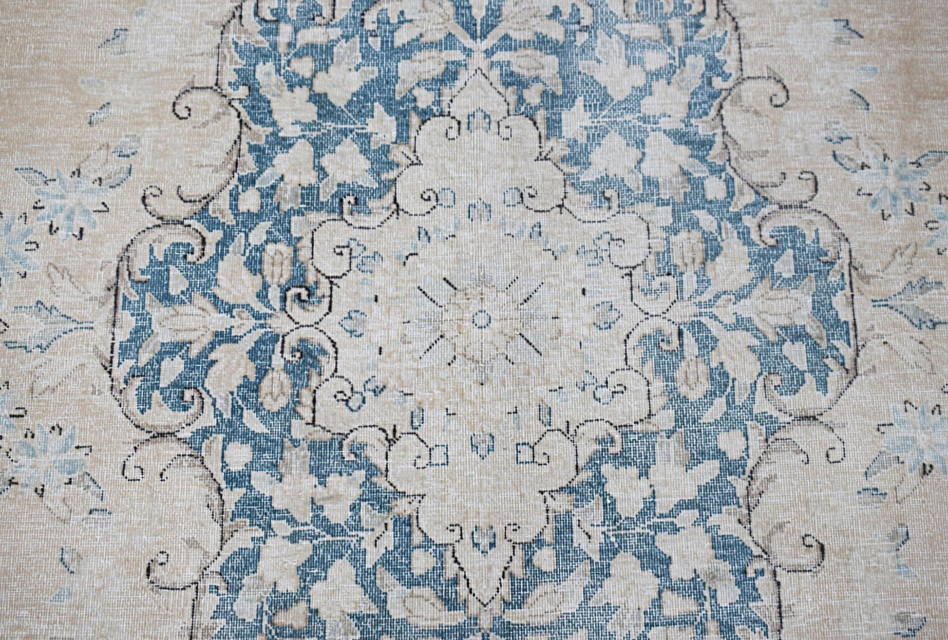 A vintage Persian Kerman rug featuring a central floral medallion in blue and cream tones.