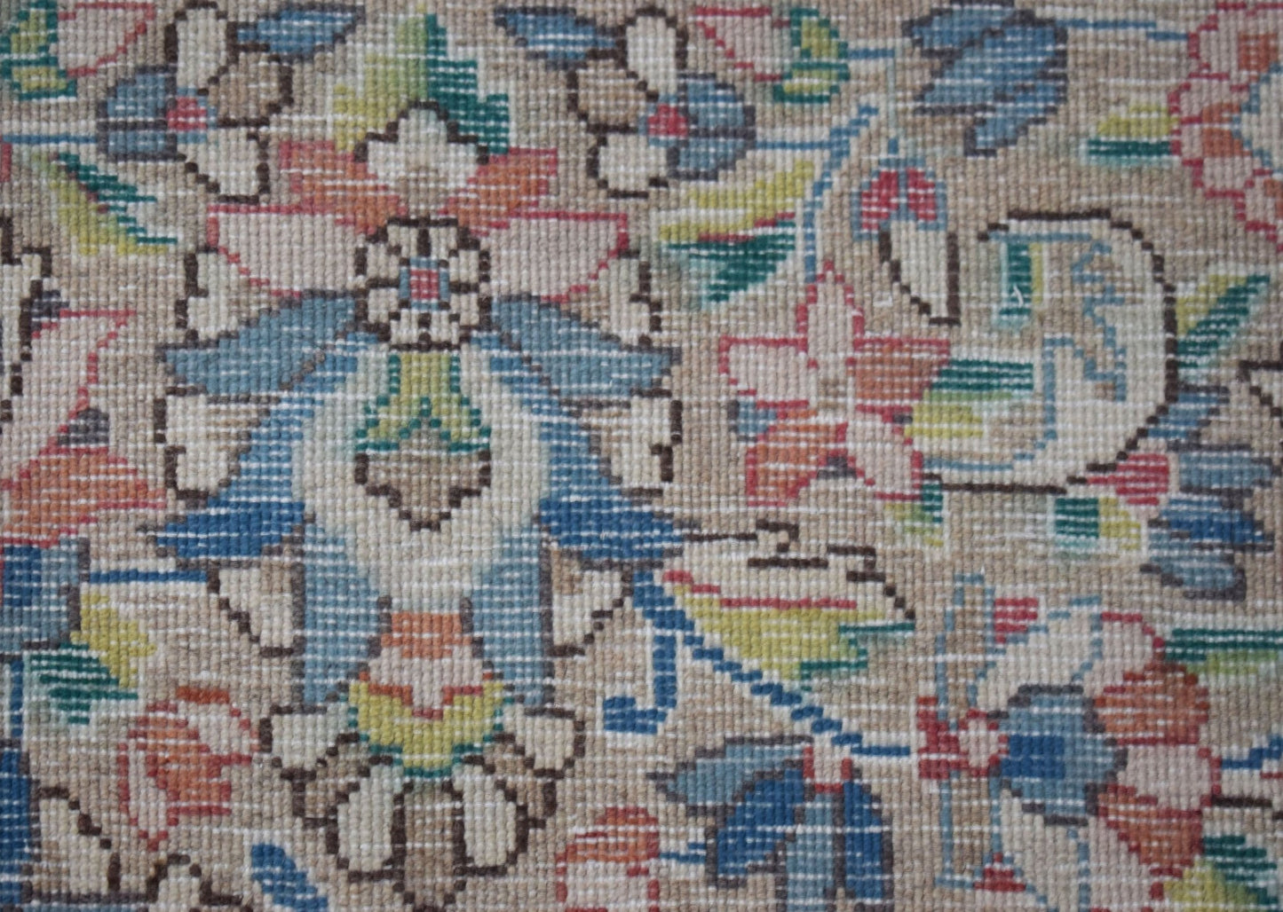 A close-up of a vintage Persian Kerman rug featuring intricate floral patterns in soft colors.