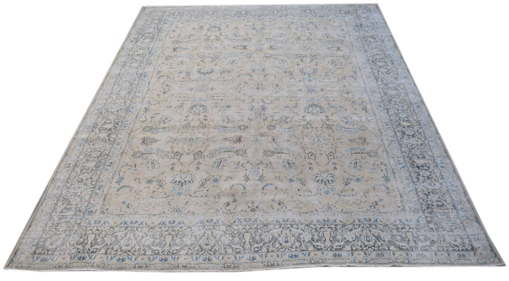 A vintage Persian Kerman rug featuring a light beige field with intricate blue floral patterns.