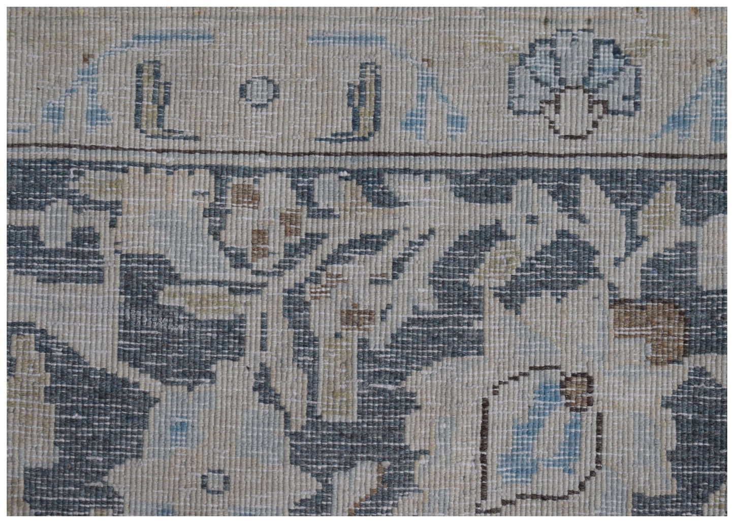 A close-up of a vintage Persian Kerman rug featuring intricate floral patterns in blue and beige.