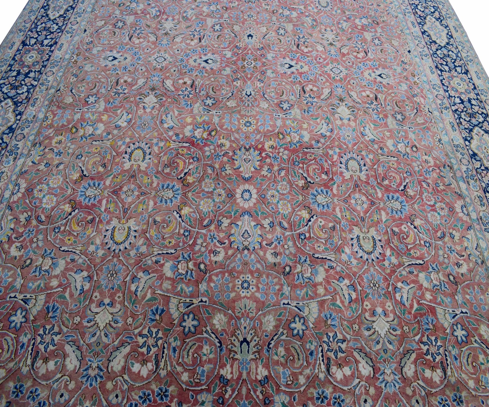 A vintage Persian Kerman rug featuring an intricate floral pattern in soft pink and blue tones.
