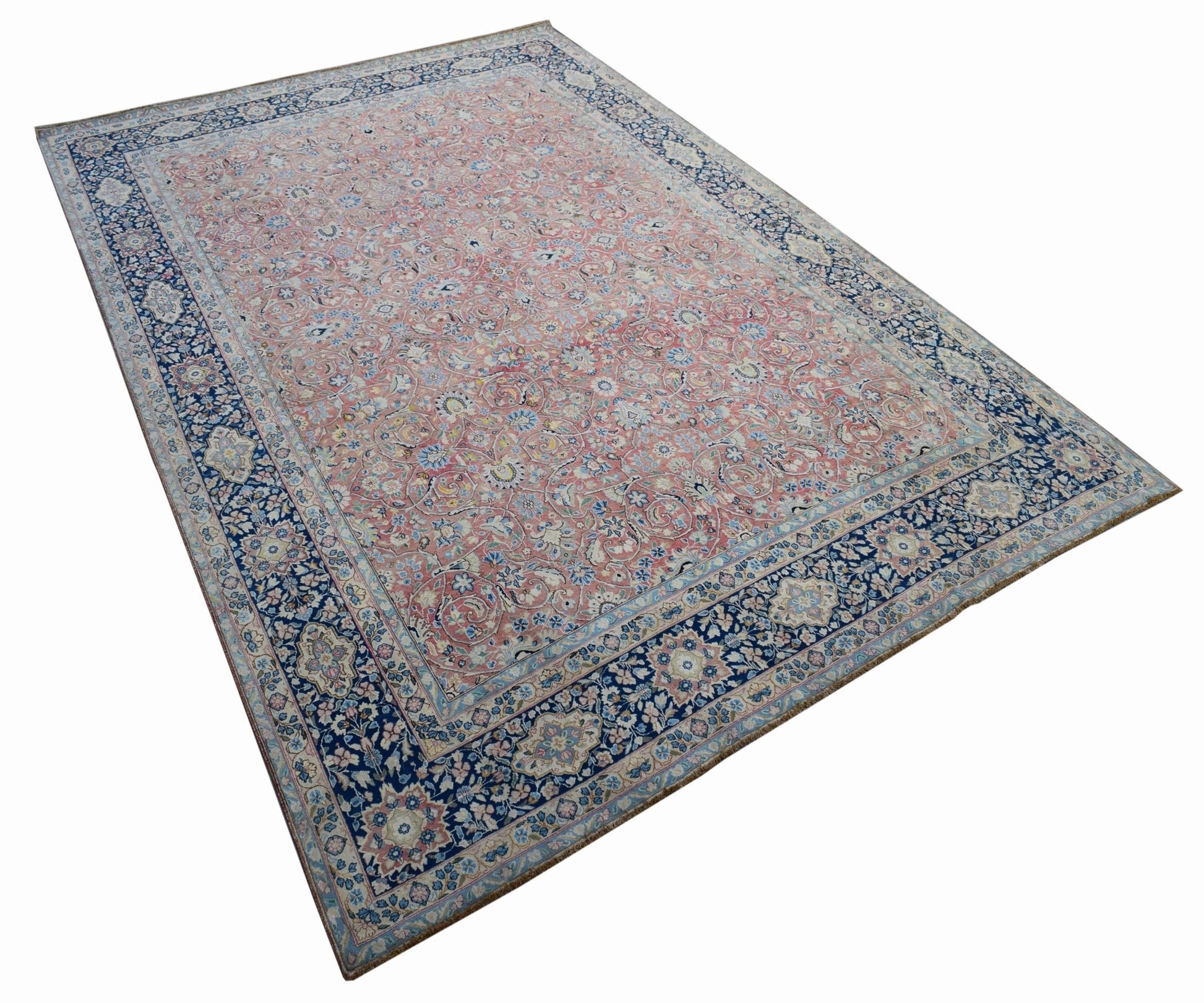 A vintage Persian Kerman rug featuring a pink field with intricate floral patterns and a blue border.