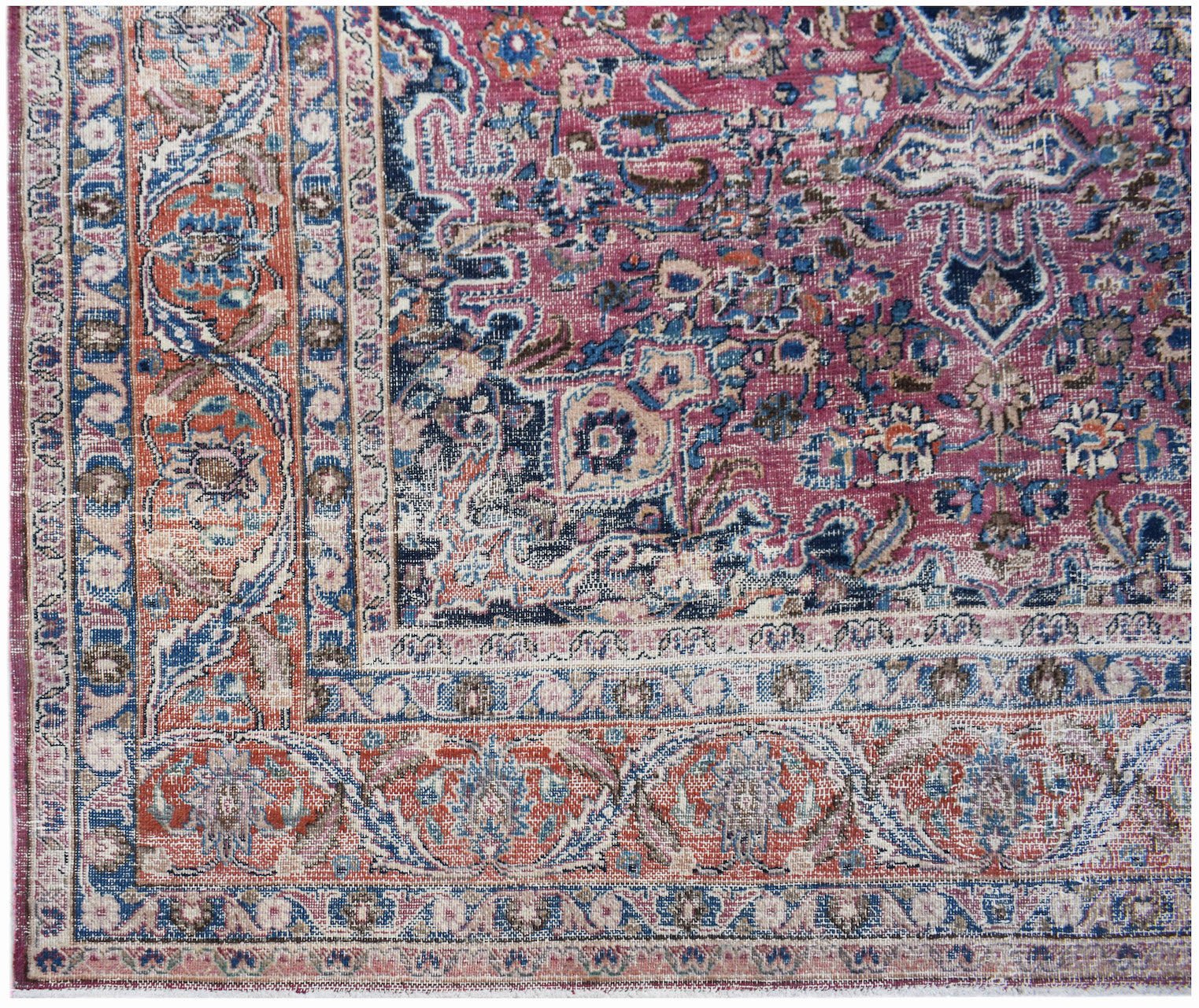 A vintage Persian Mashhad rug featuring intricate floral patterns in shades of pink, blue, and red.