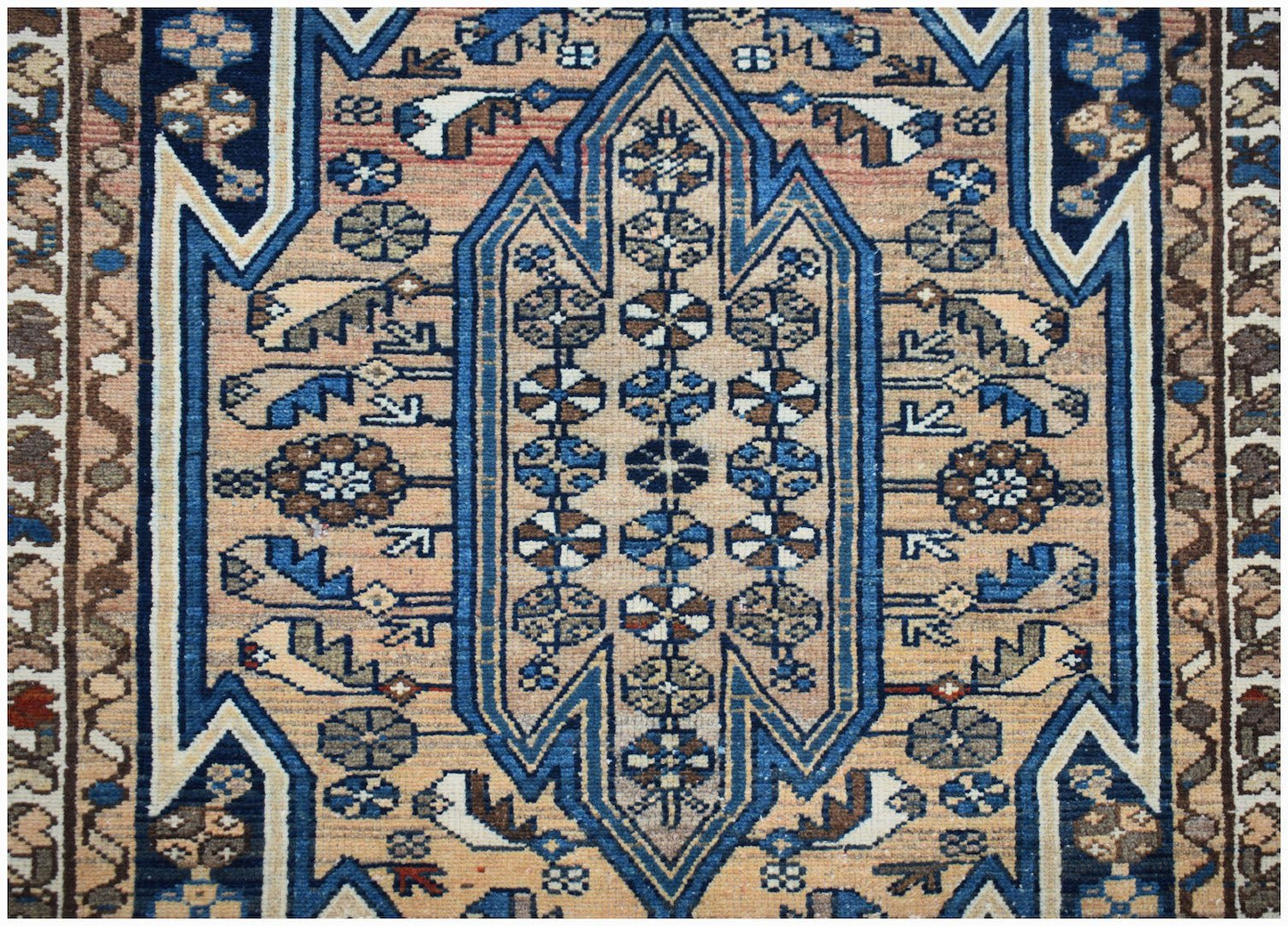 A vintage Persian Mazlaghan rug featuring a geometric blue medallion on a tan field.