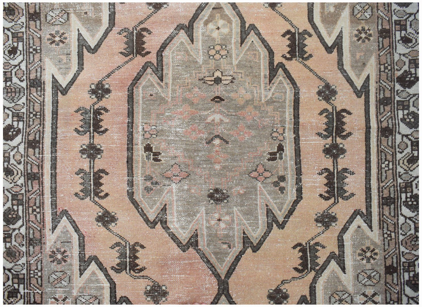 A vintage Persian Mazlaghan rug featuring a central geometric medallion in muted peach and grey.