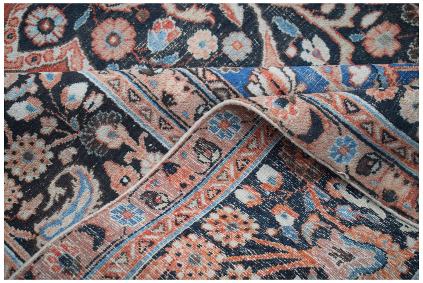 A vintage Persian Moud rug featuring intricate floral patterns in shades of blue, orange, and black.