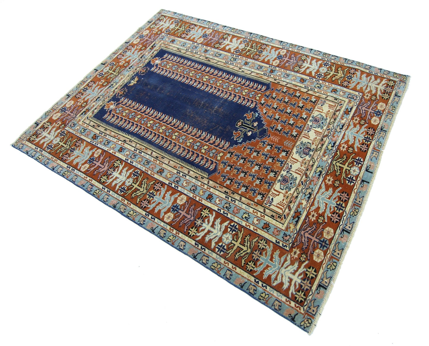 A vintage Persian prayer rug featuring a central blue mihrab design on a patterned rust background.