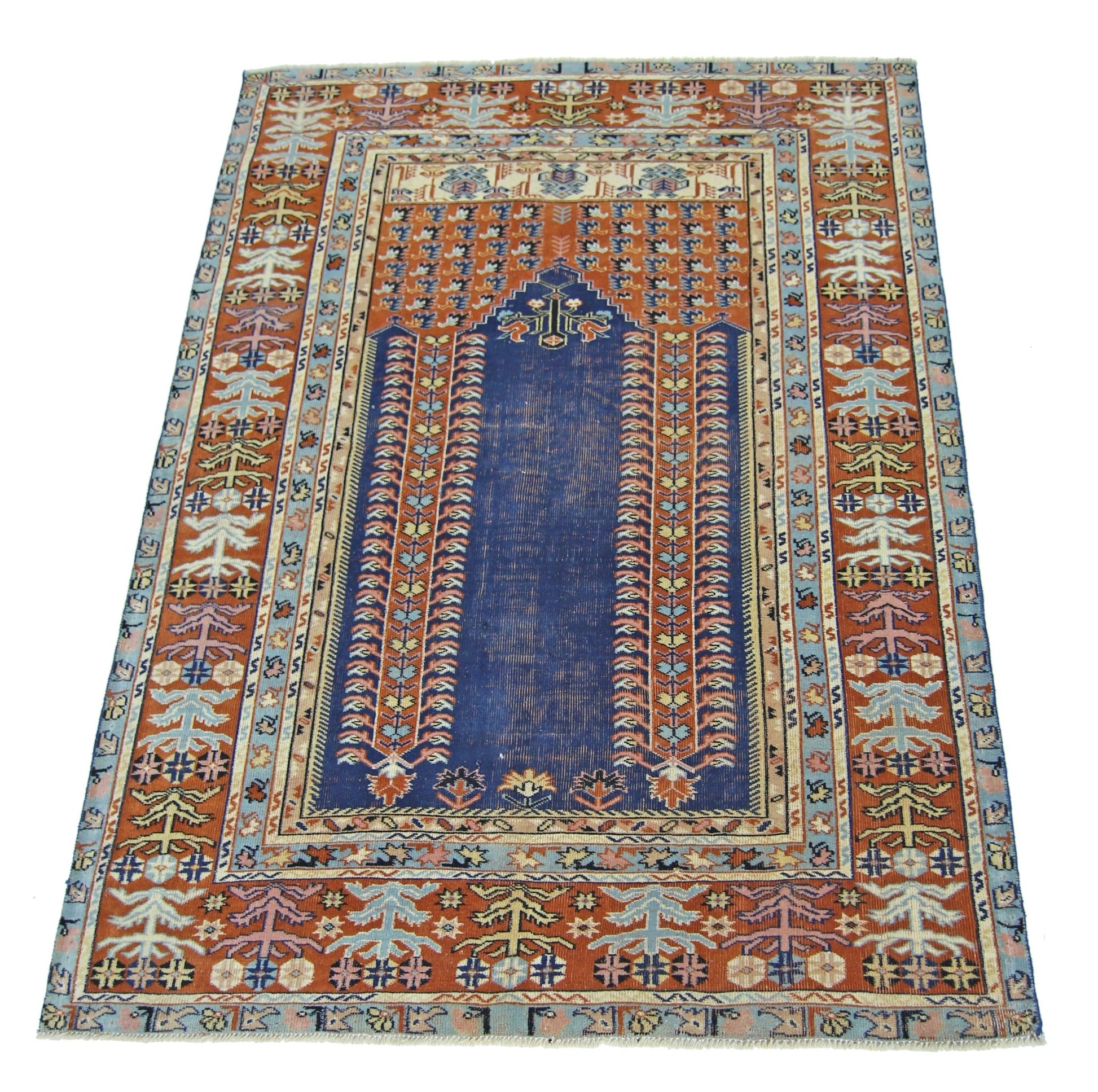 A vintage Persian prayer rug featuring a central blue mihrab design on a rust-colored field.