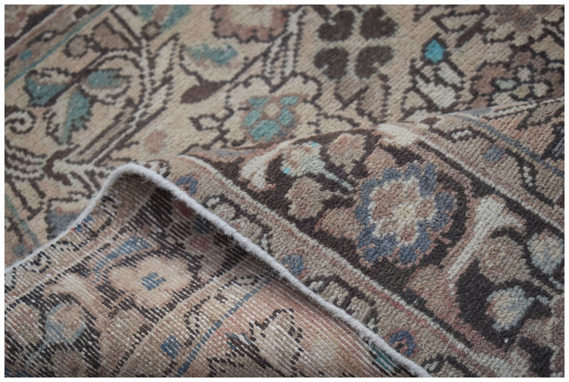 A handwoven vintage Persian rug featuring a faded floral pattern in muted earth tones.