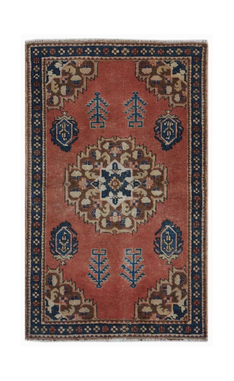 A vintage handwoven Persian rug featuring a central floral medallion on a terracotta field.