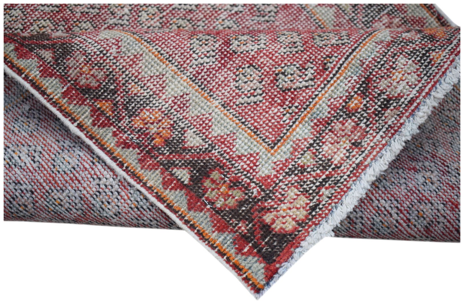 A handwoven vintage Persian rug featuring a red and cream geometric pattern on a wool pile.