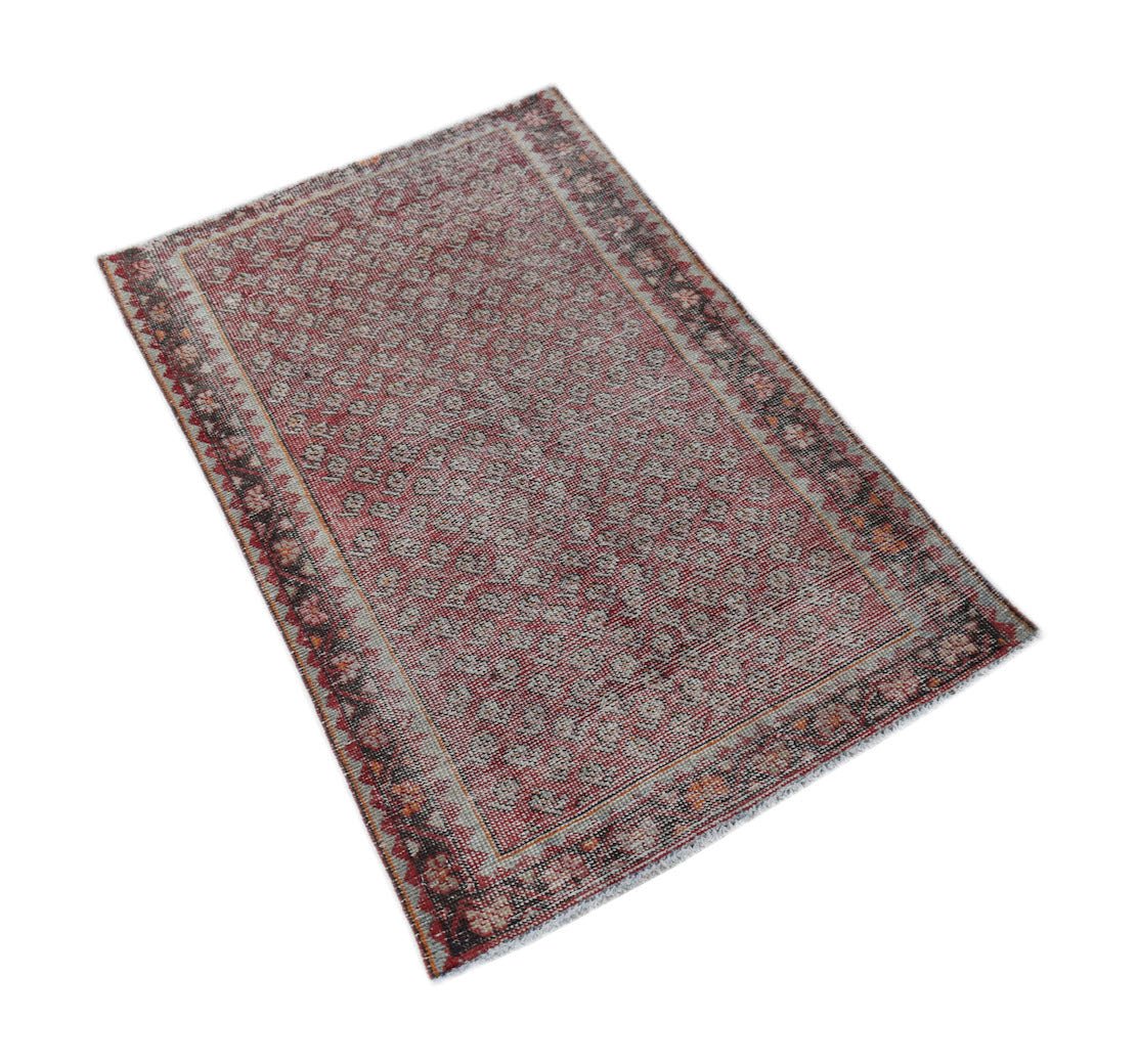 A rectangular vintage Persian rug featuring a faded red pattern with a decorative border.