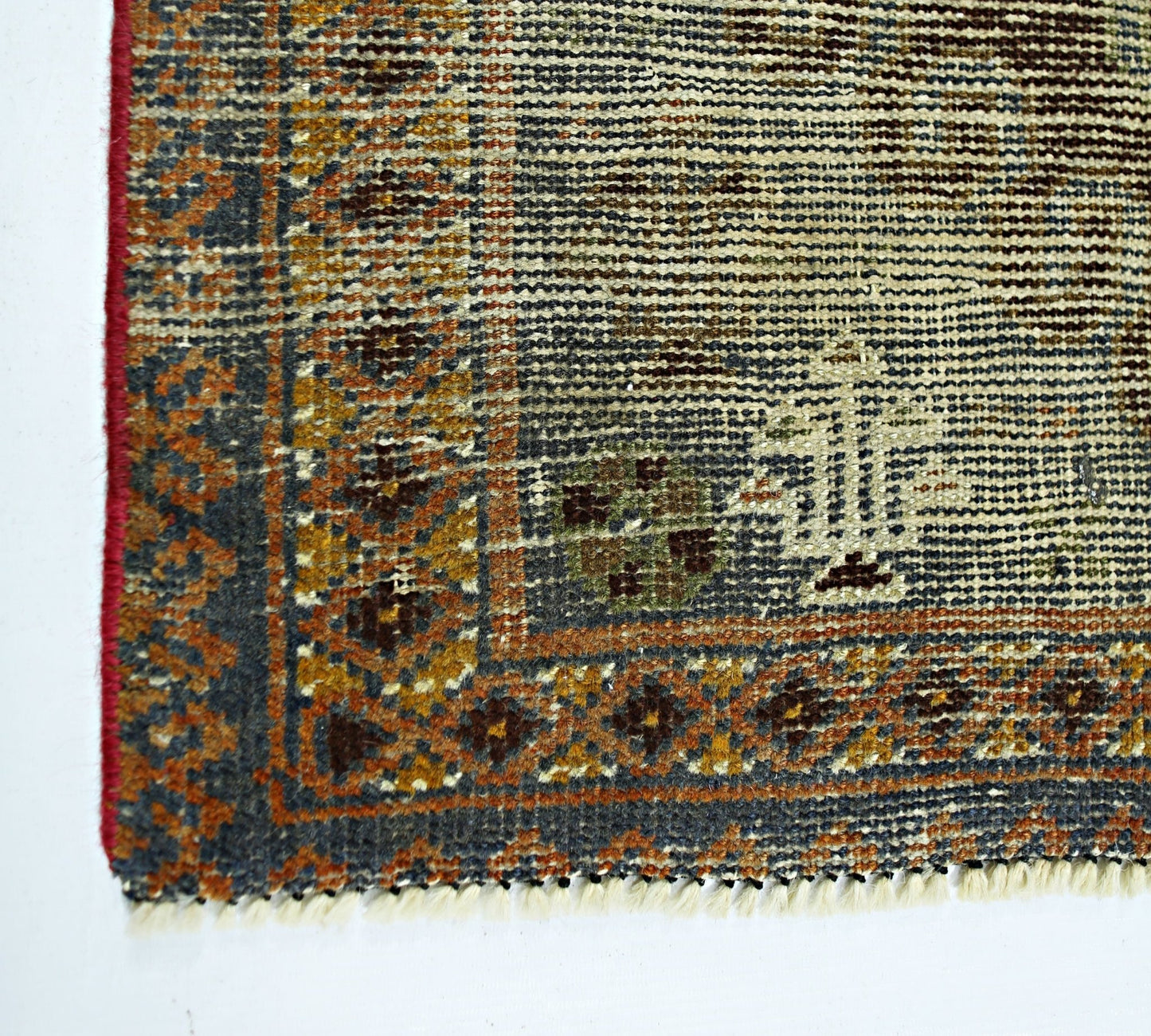 A corner view of a vintage handmade Persian wool rug featuring intricate geometric patterns.