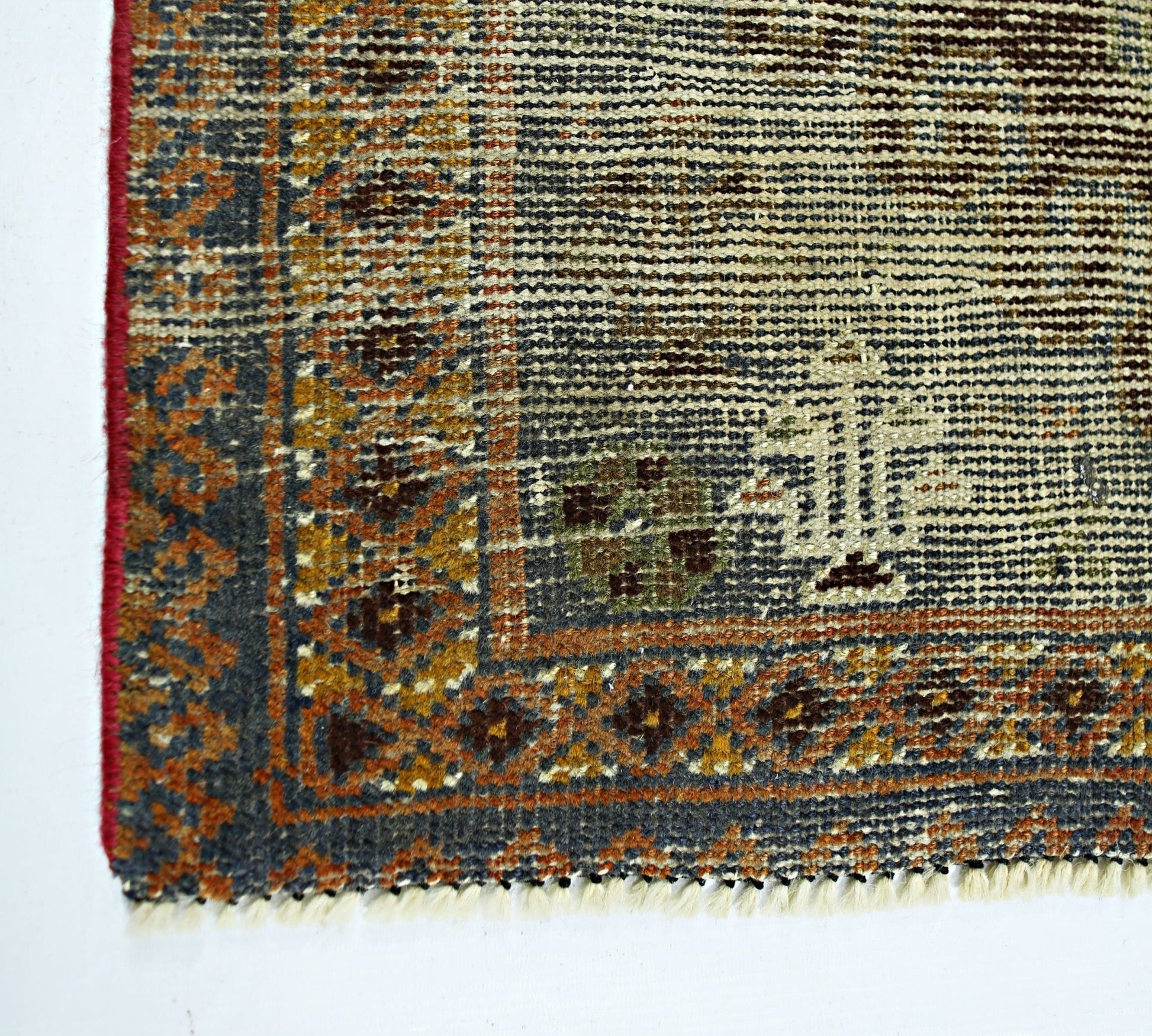 A corner view of a vintage handmade Persian wool rug featuring intricate geometric patterns.