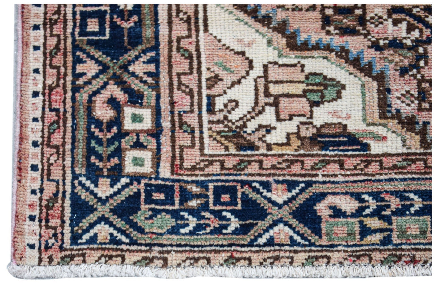 A close-up of a handwoven vintage Persian rug featuring intricate geometric patterns in blue and pink.