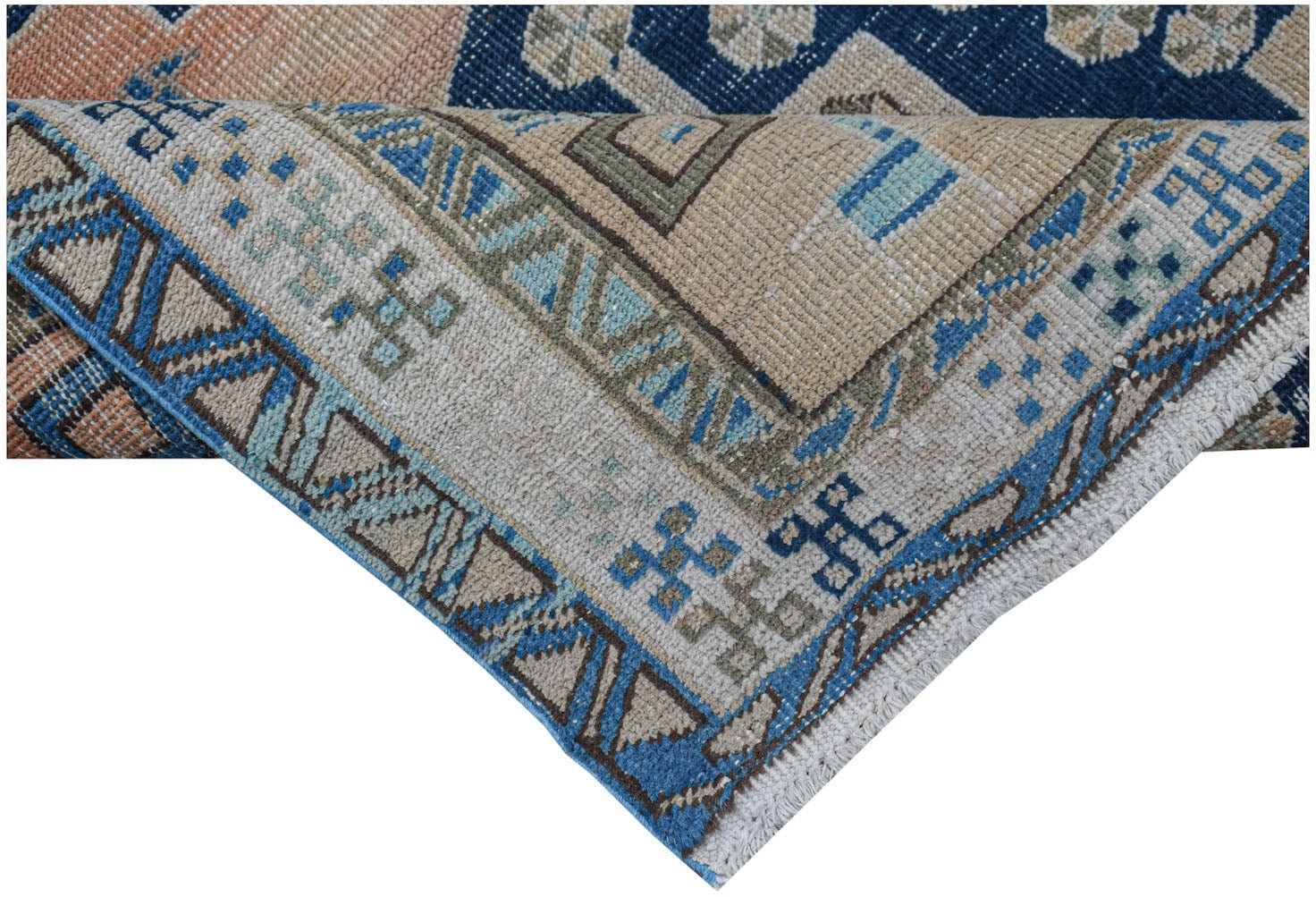 A corner view of a handwoven vintage Persian rug featuring geometric patterns in blue and beige.