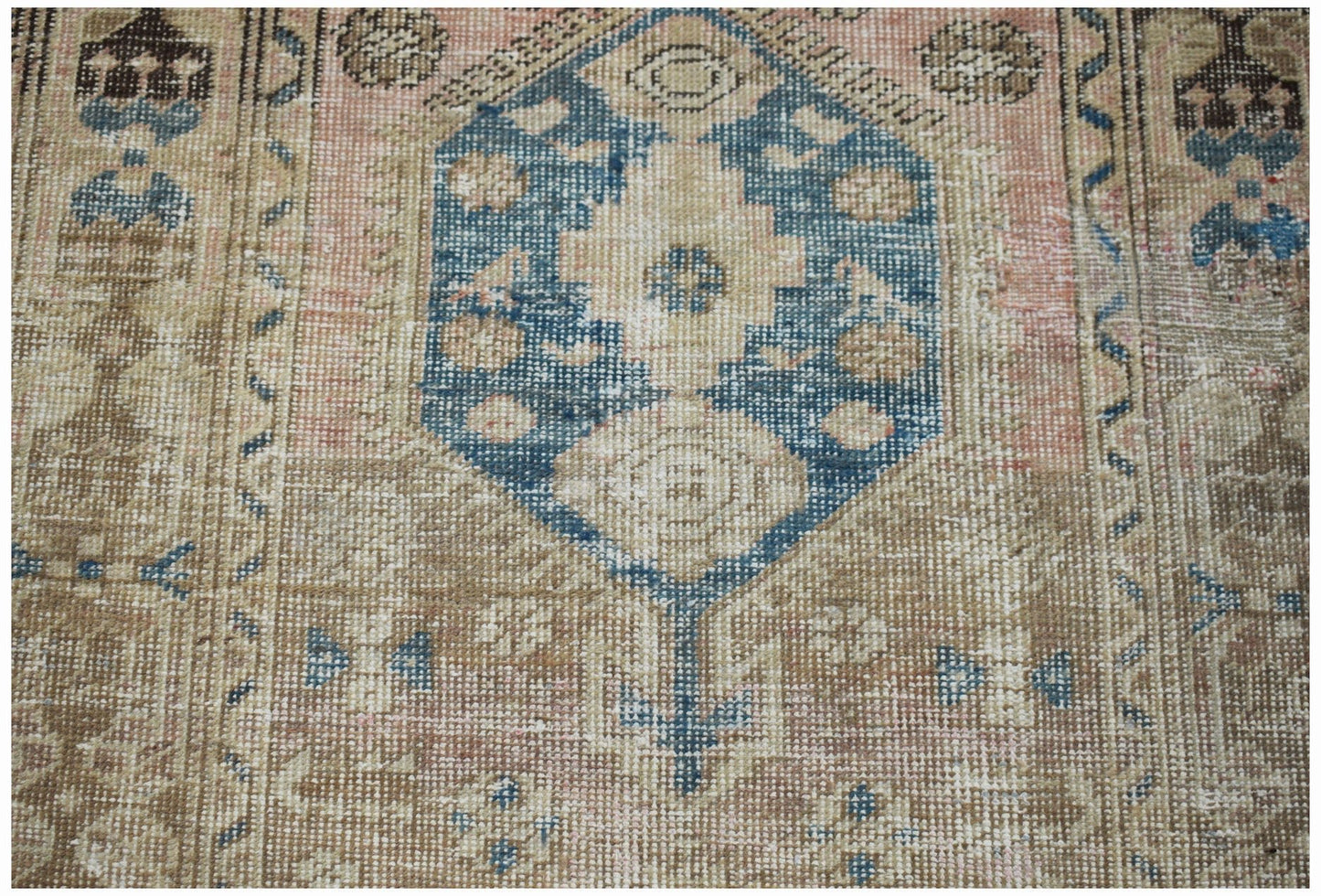 A vintage handwoven Persian Hamadan rug featuring a central blue medallion on a faded floral field.