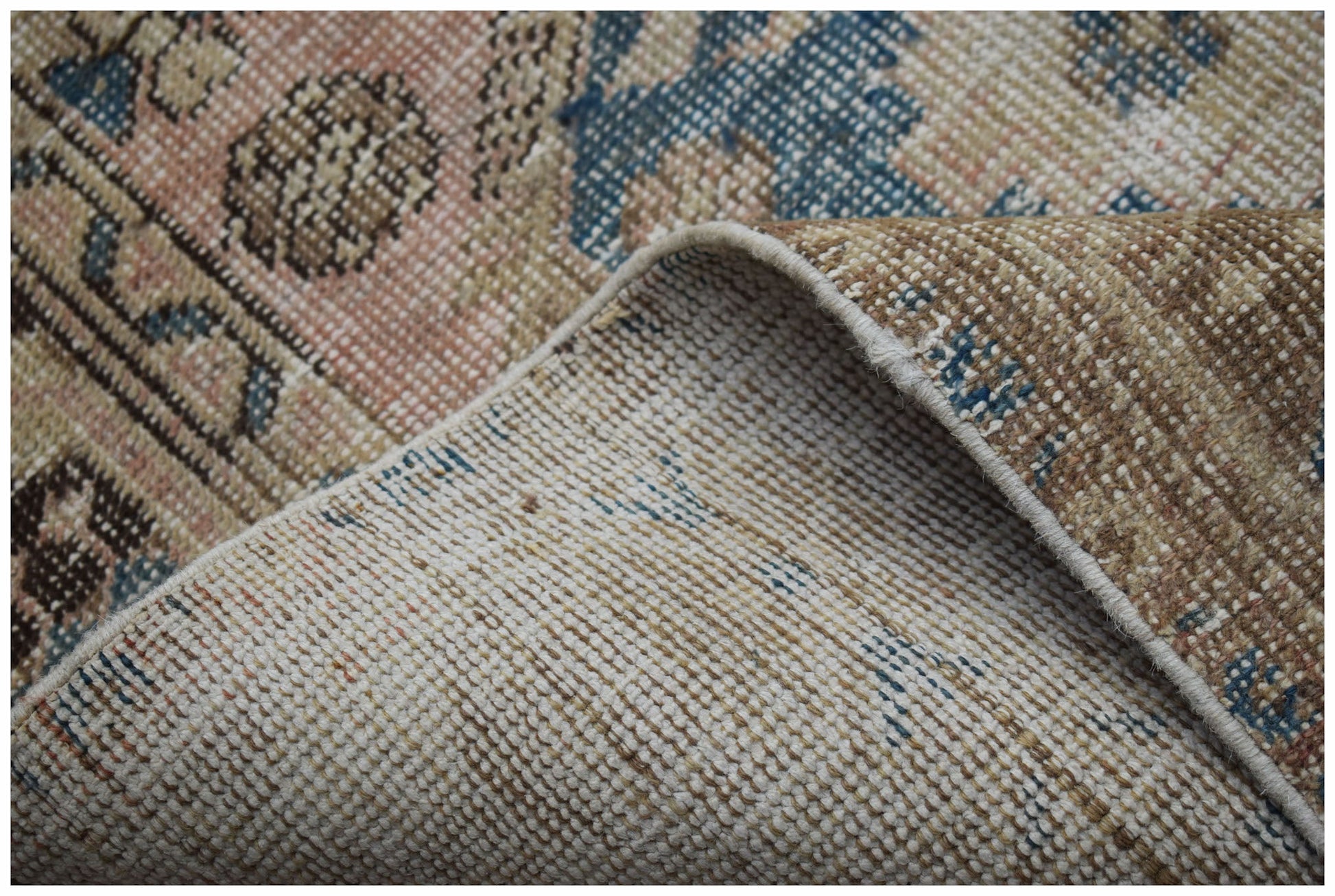 A corner of a vintage Persian Hamadan rug showing its handwoven wool pile and cotton backing.
