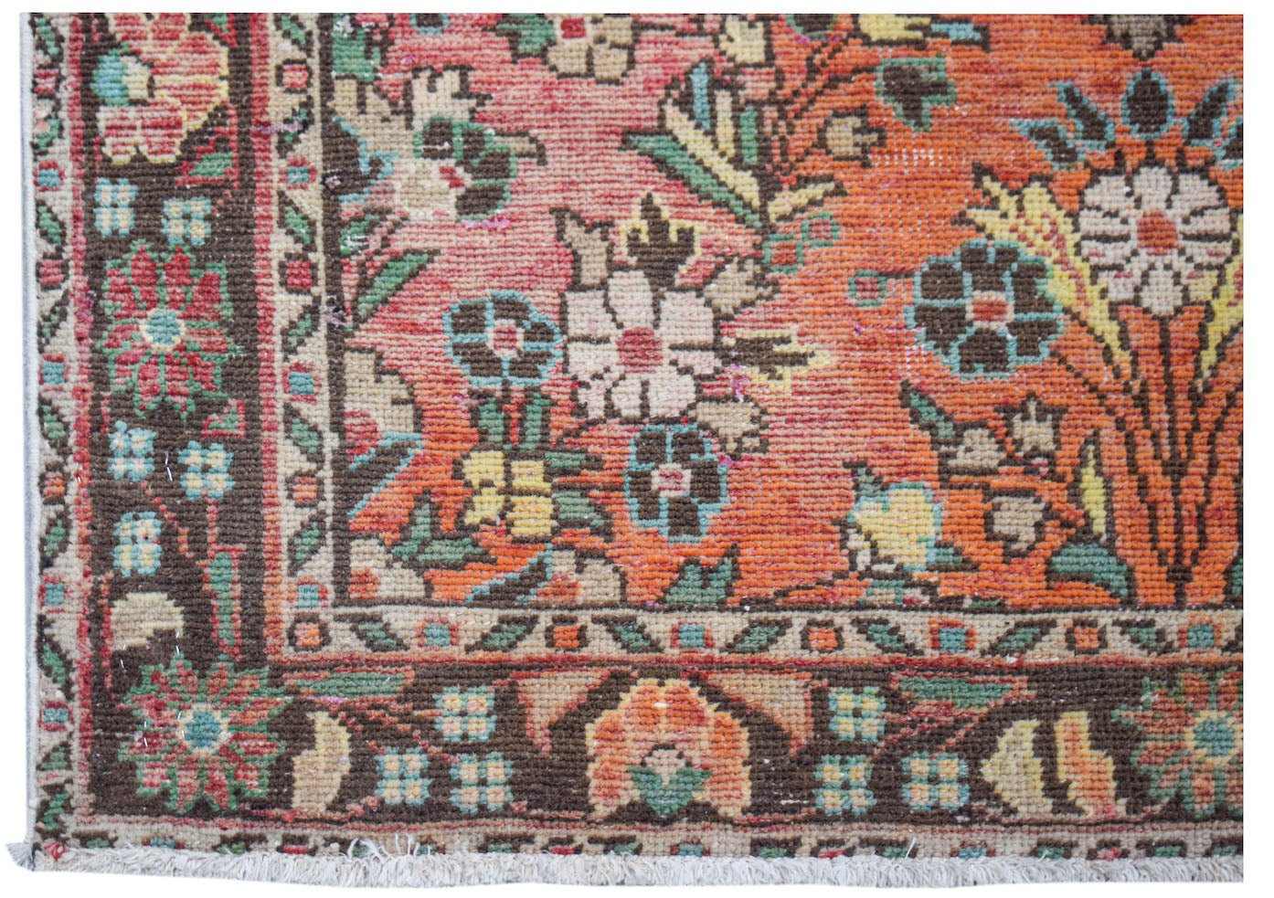 A handwoven vintage Persian rug featuring a floral pattern in orange, brown, and green tones.