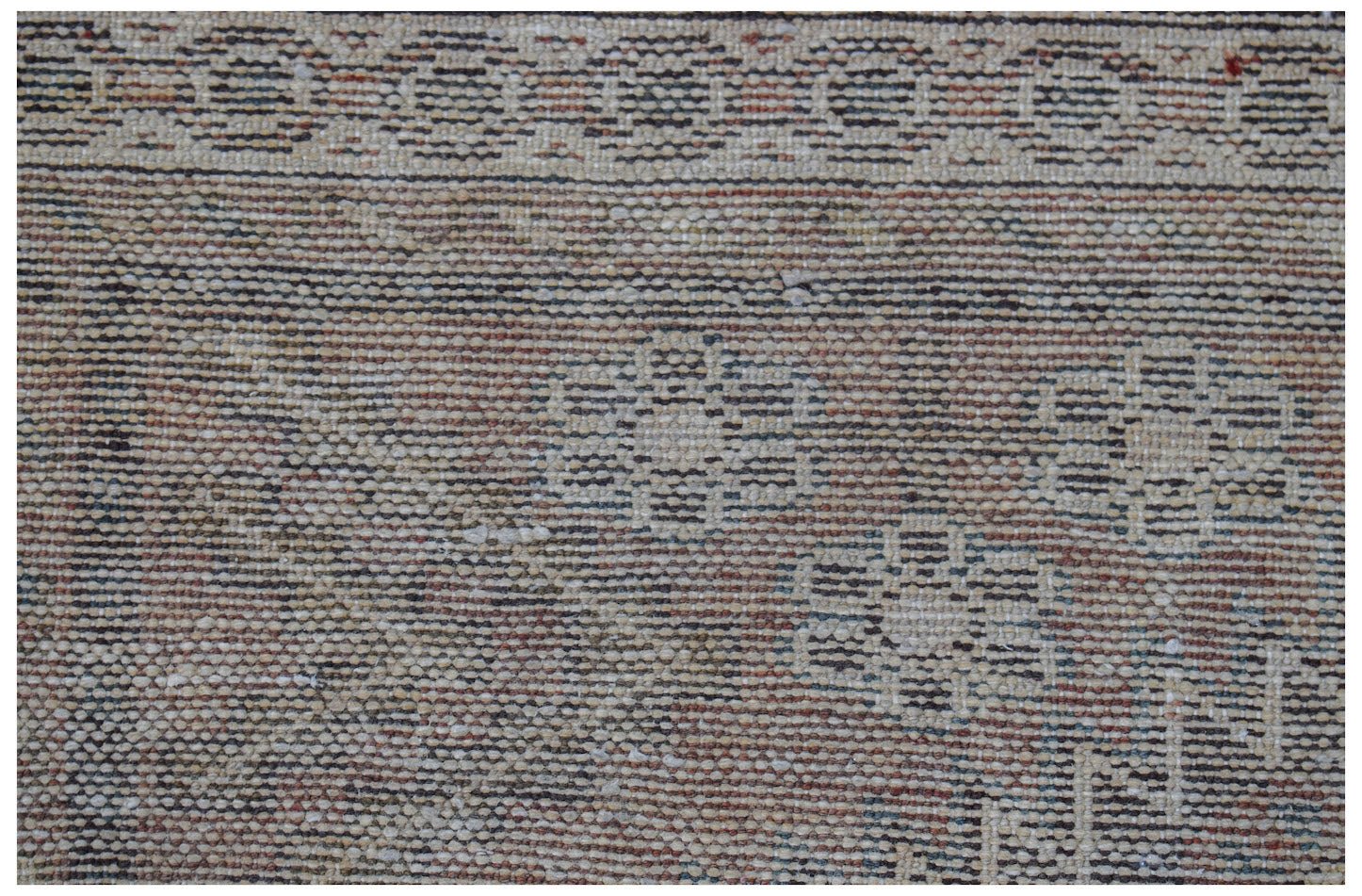 A close-up of a vintage handwoven Persian rug featuring a faded floral pattern and border.