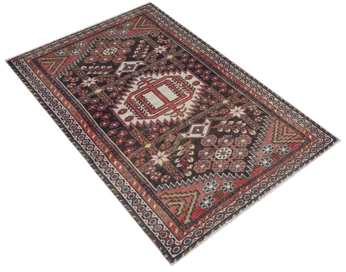 A handwoven vintage Persian rug featuring a dark field with geometric patterns and floral motifs.