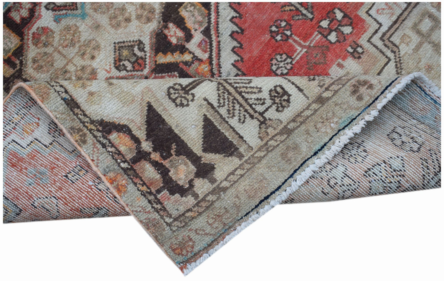 A vintage handwoven Persian rug with a worn texture and traditional geometric floral patterns.