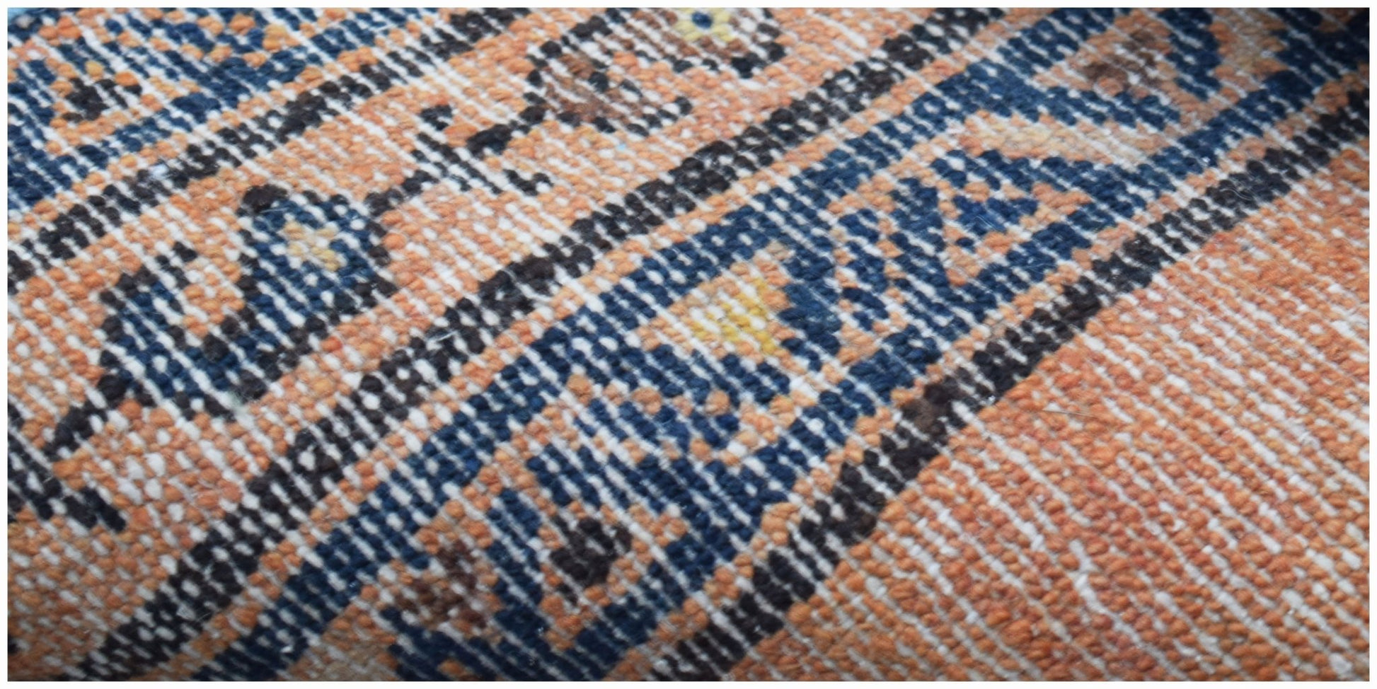 A close-up view of a vintage Persian rug featuring intricate blue and orange geometric patterns.