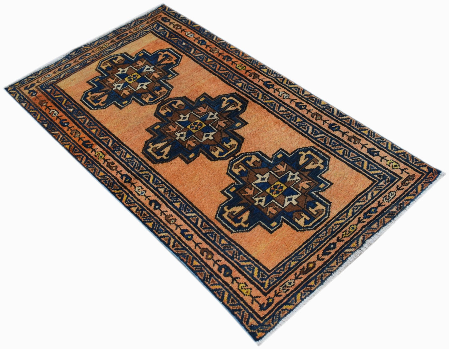 A vintage handwoven Persian rug featuring three dark blue geometric medallions on an orange field.
