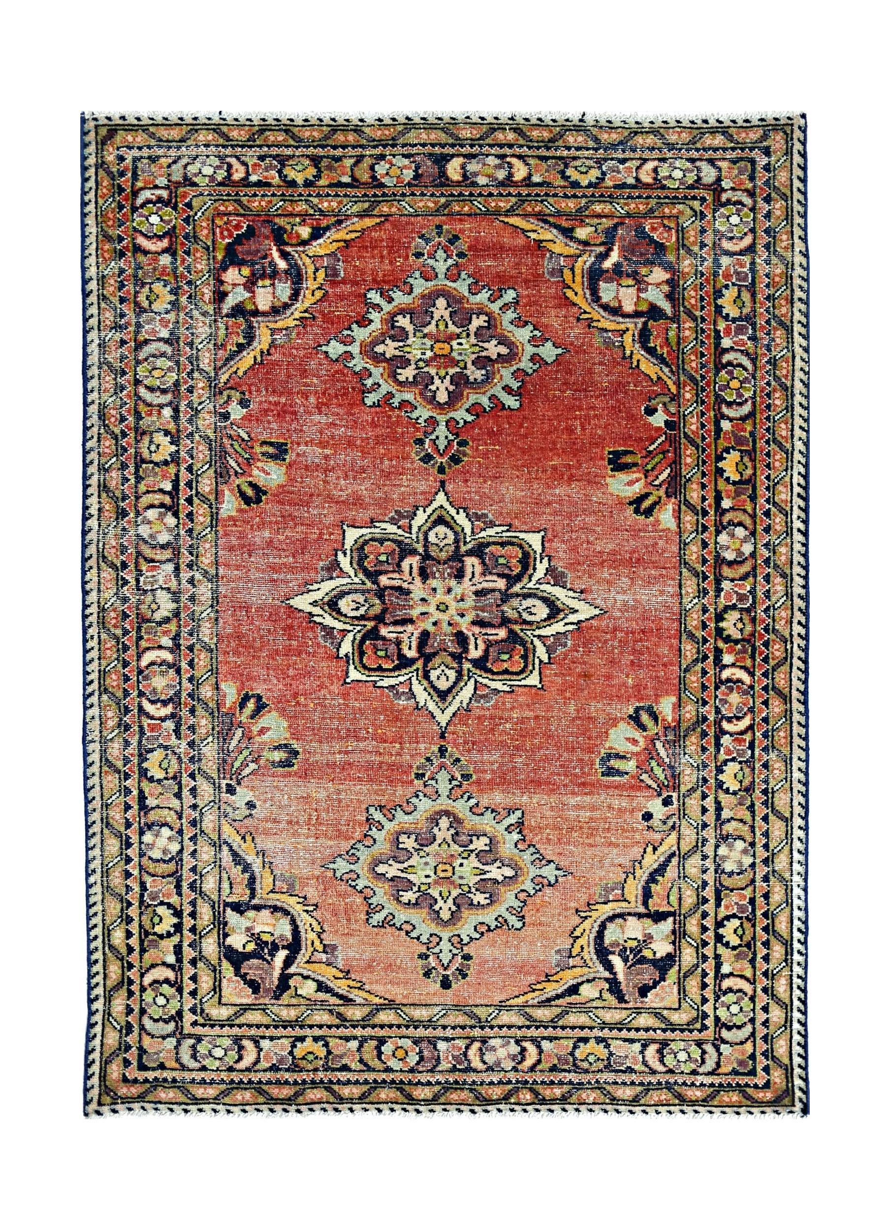 A vintage handmade Persian rug featuring a central floral medallion on a faded red field.
