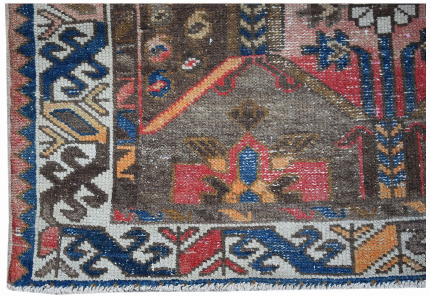 A handwoven vintage Persian rug featuring a geometric pattern in red, blue, and brown tones.