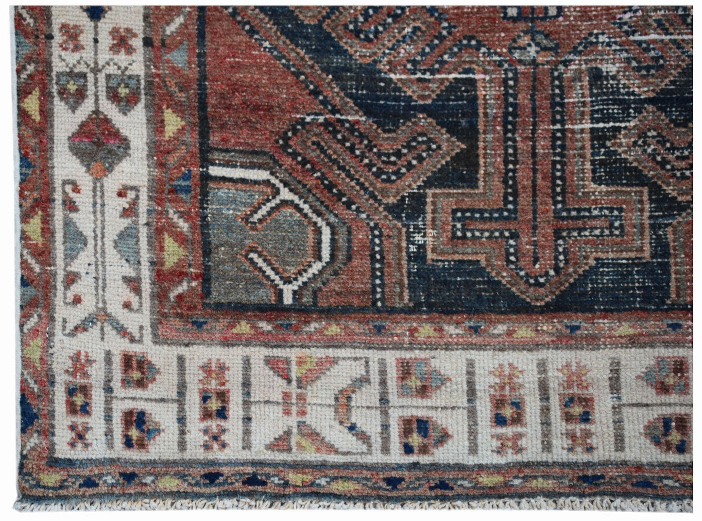A handwoven vintage Persian rug featuring a geometric pattern in red, blue, and cream tones.