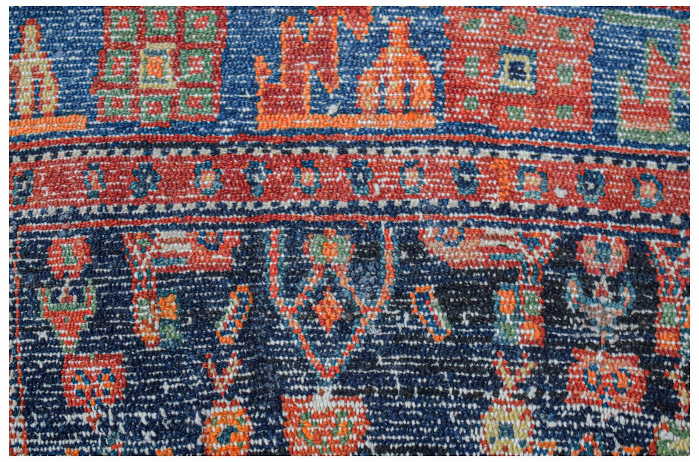 A close-up of a handwoven vintage Persian rug featuring intricate geometric patterns in blue and red.