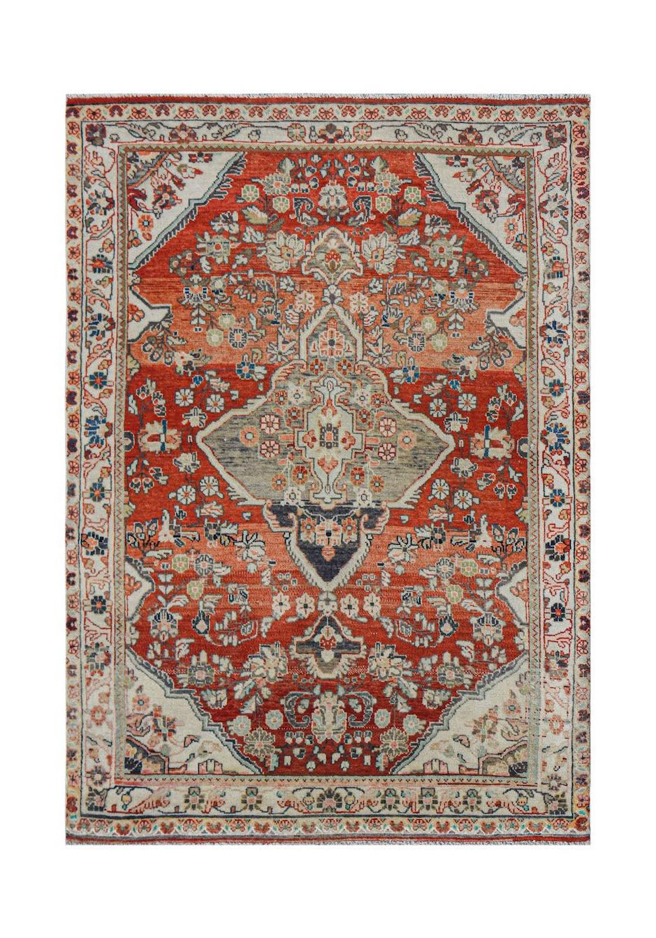 A handwoven vintage Persian rug featuring a central medallion on a red field with floral patterns.