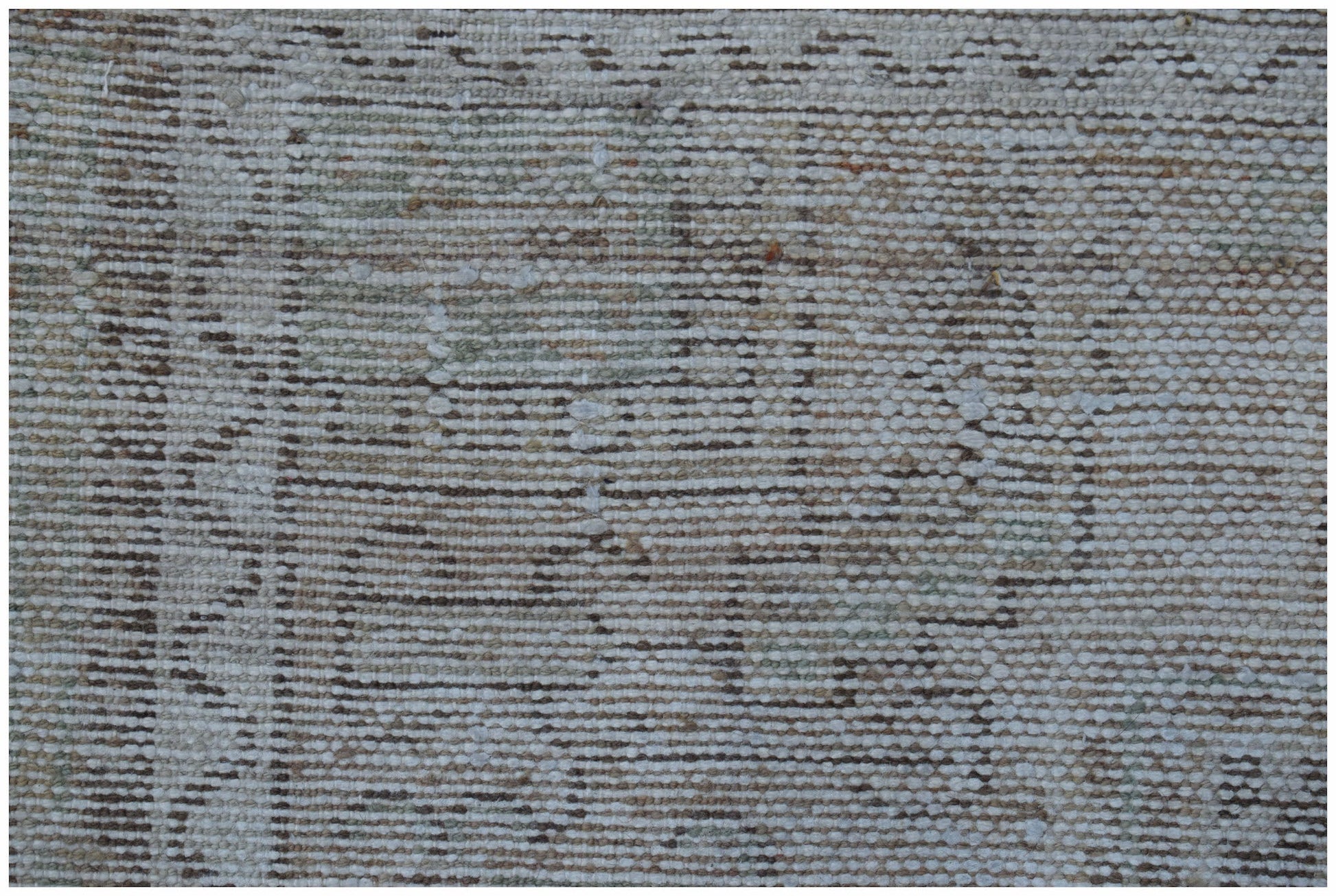 A close-up view of a handwoven vintage Persian rug featuring a faded, distressed geometric pattern.
