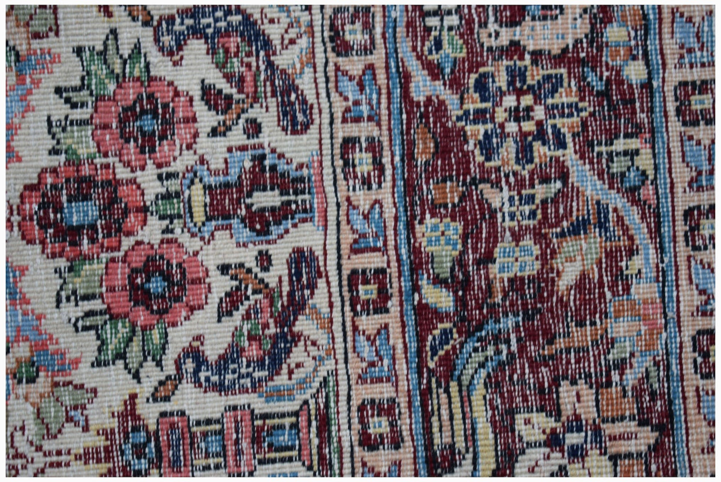A vintage handwoven Persian rug featuring intricate floral patterns in red, blue, and cream tones.