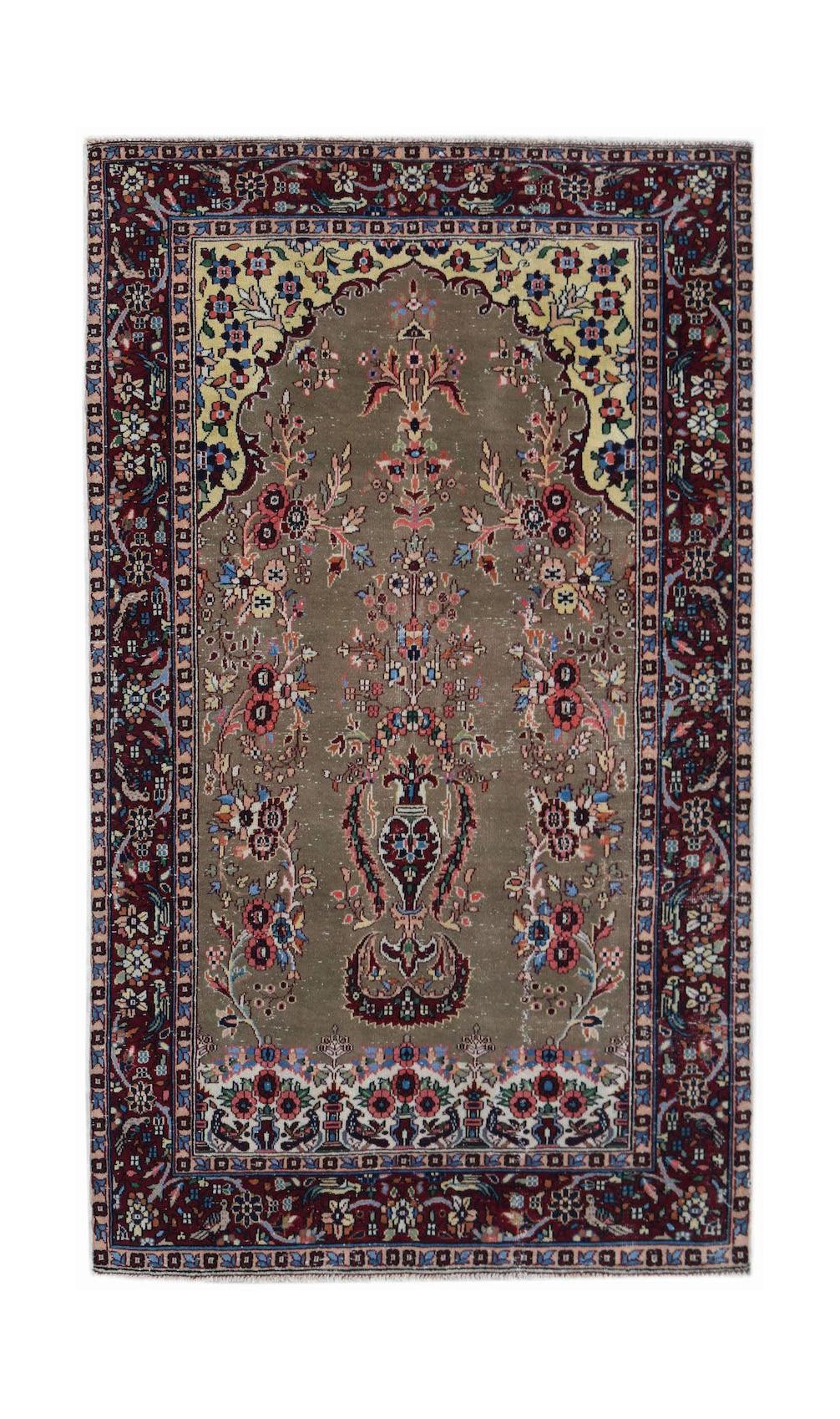 A vintage handwoven Persian rug featuring a central floral motif on a taupe field with a dark border.