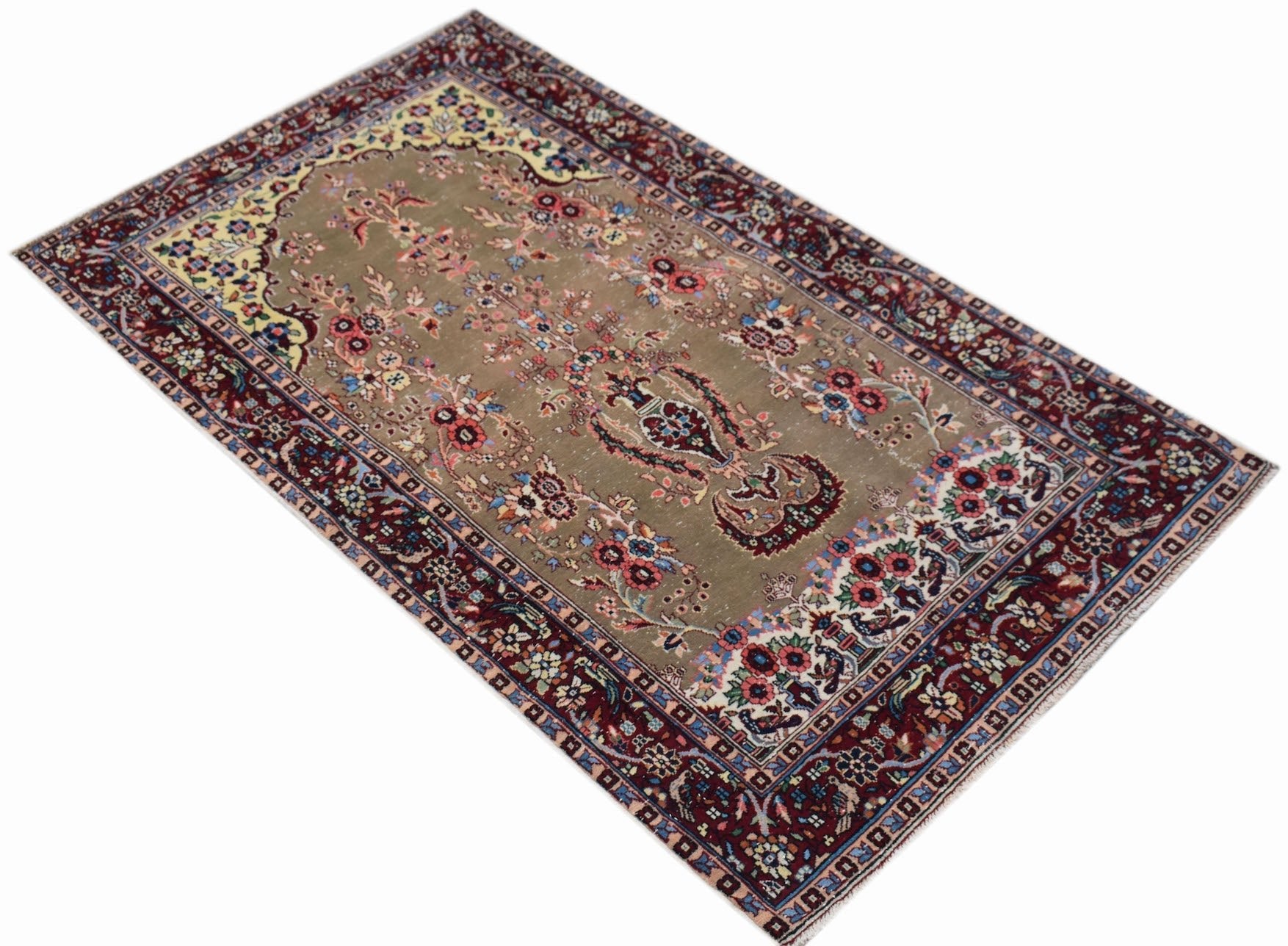 A vintage handwoven Persian rug featuring a floral pattern on a muted olive field with red borders.