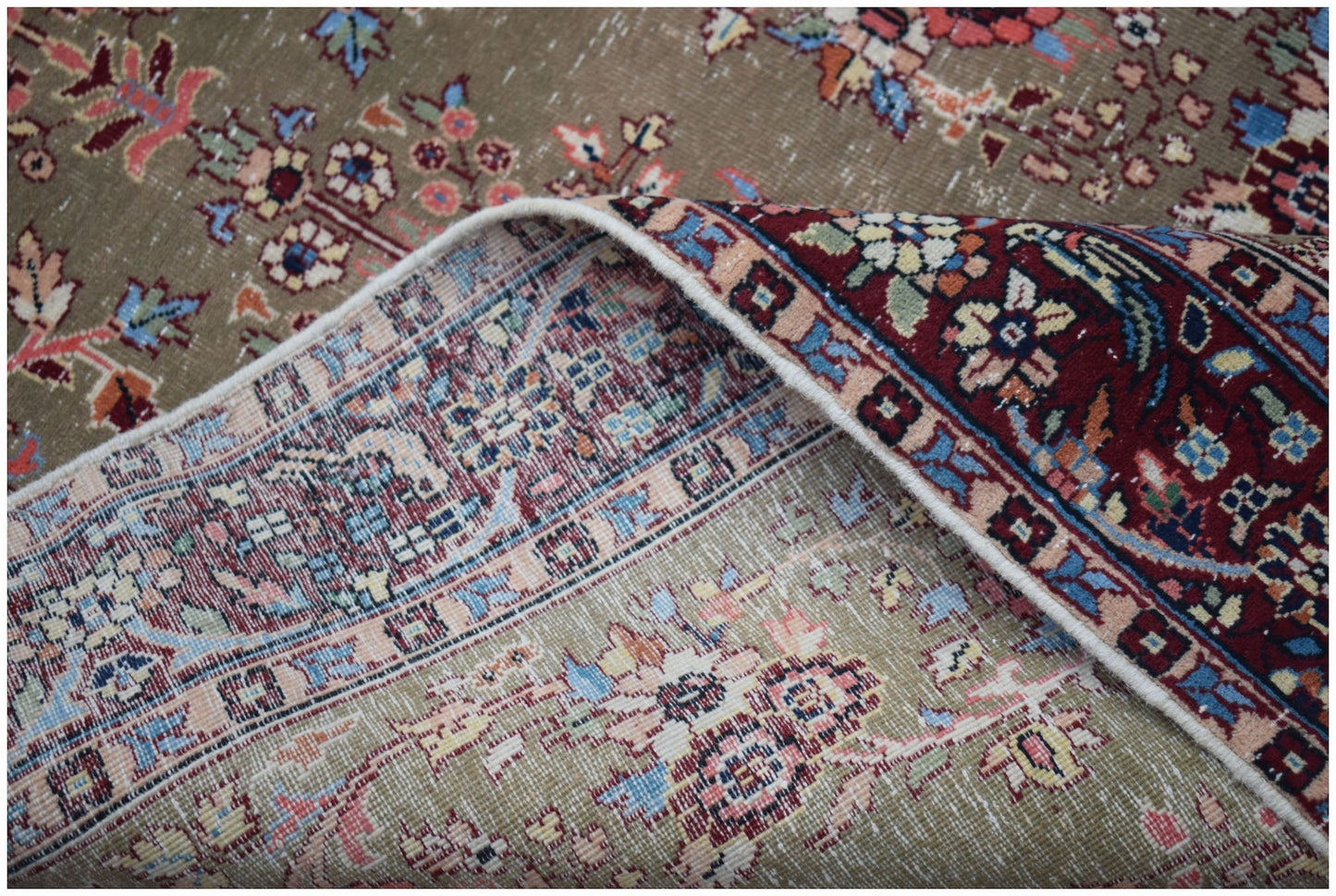 A vintage handwoven Persian rug with a distressed olive green field and a deep red border.