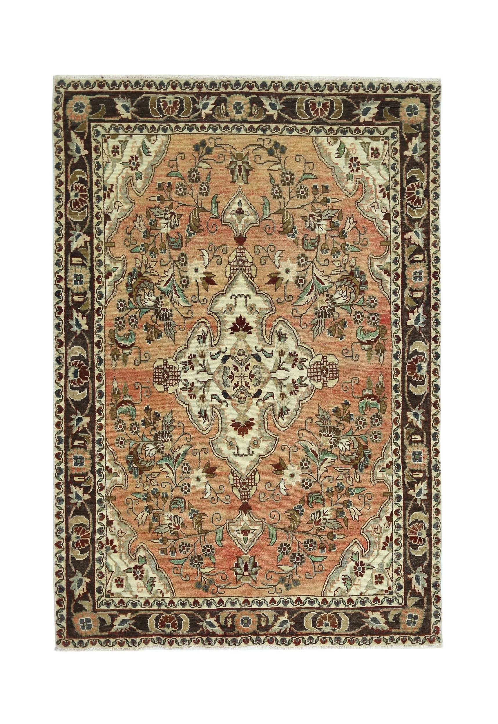 A vintage Persian Sarouk rug featuring a central floral medallion on a salmon field.